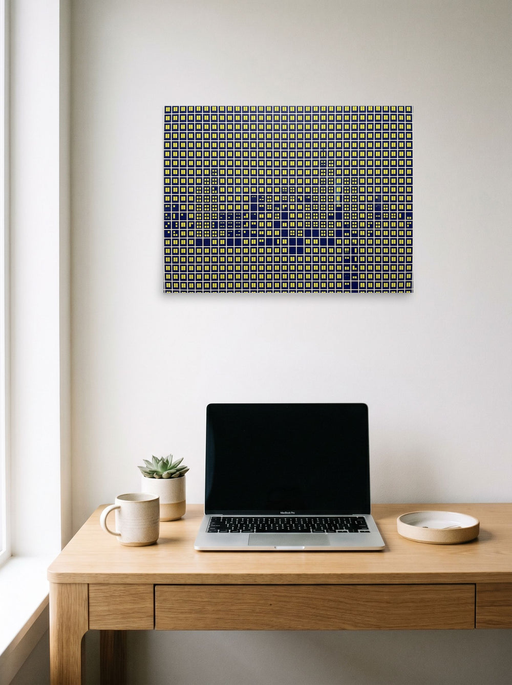 A 24x18 inch unframed paper Pop art print of 'Illuminated Grid' hanging above a worktable with a laptop.