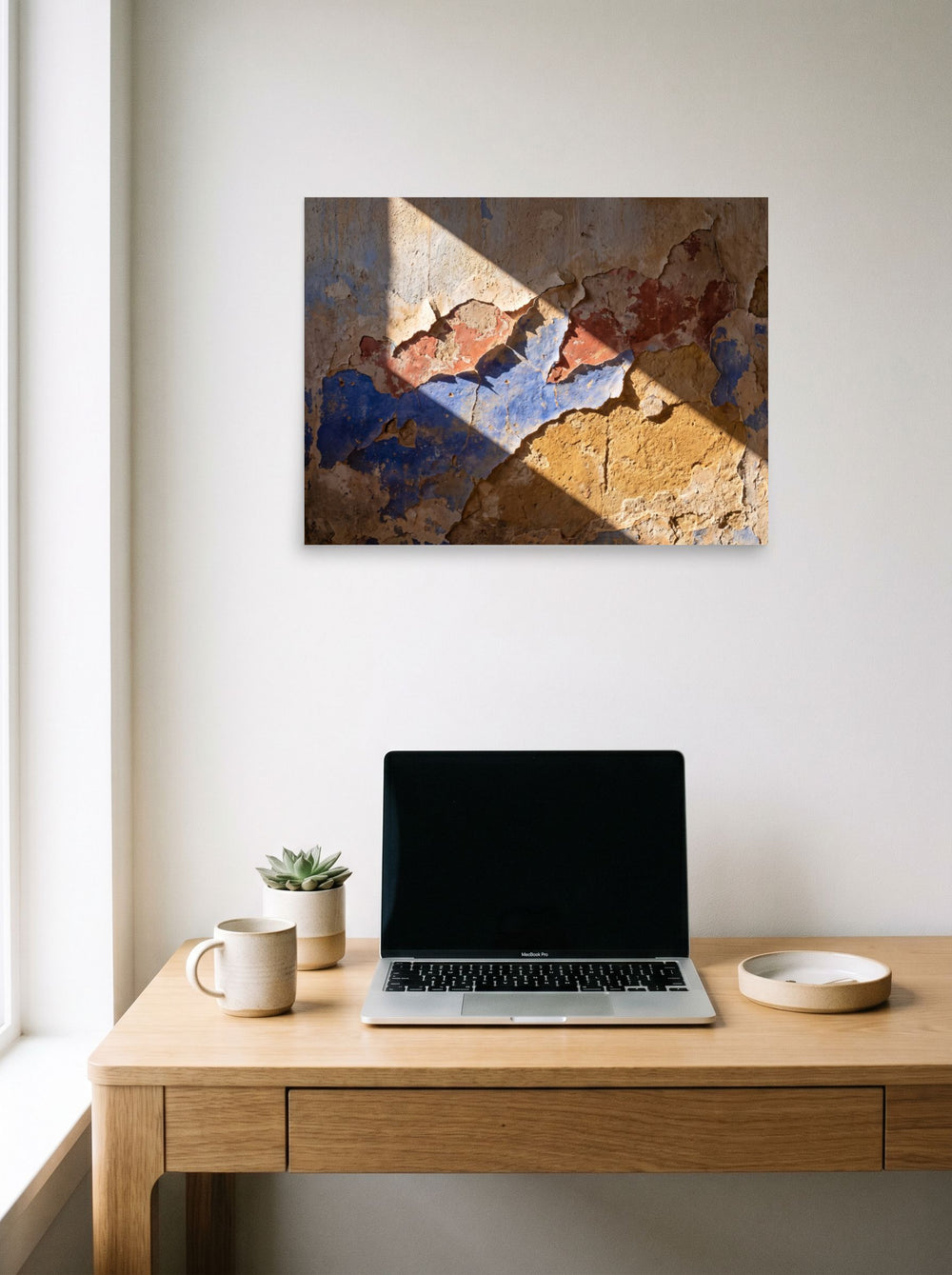A 24x18 inch unframed paper Art photography print of 'Palimpsest in Sunlight' hanging above a worktable with a laptop.