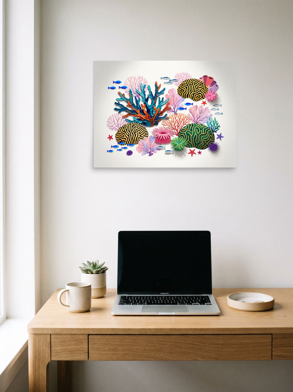 Assemblage wall art 'Reef Symphony', unframed paper at 24x18 inch, hanging above a worktable with a laptop.