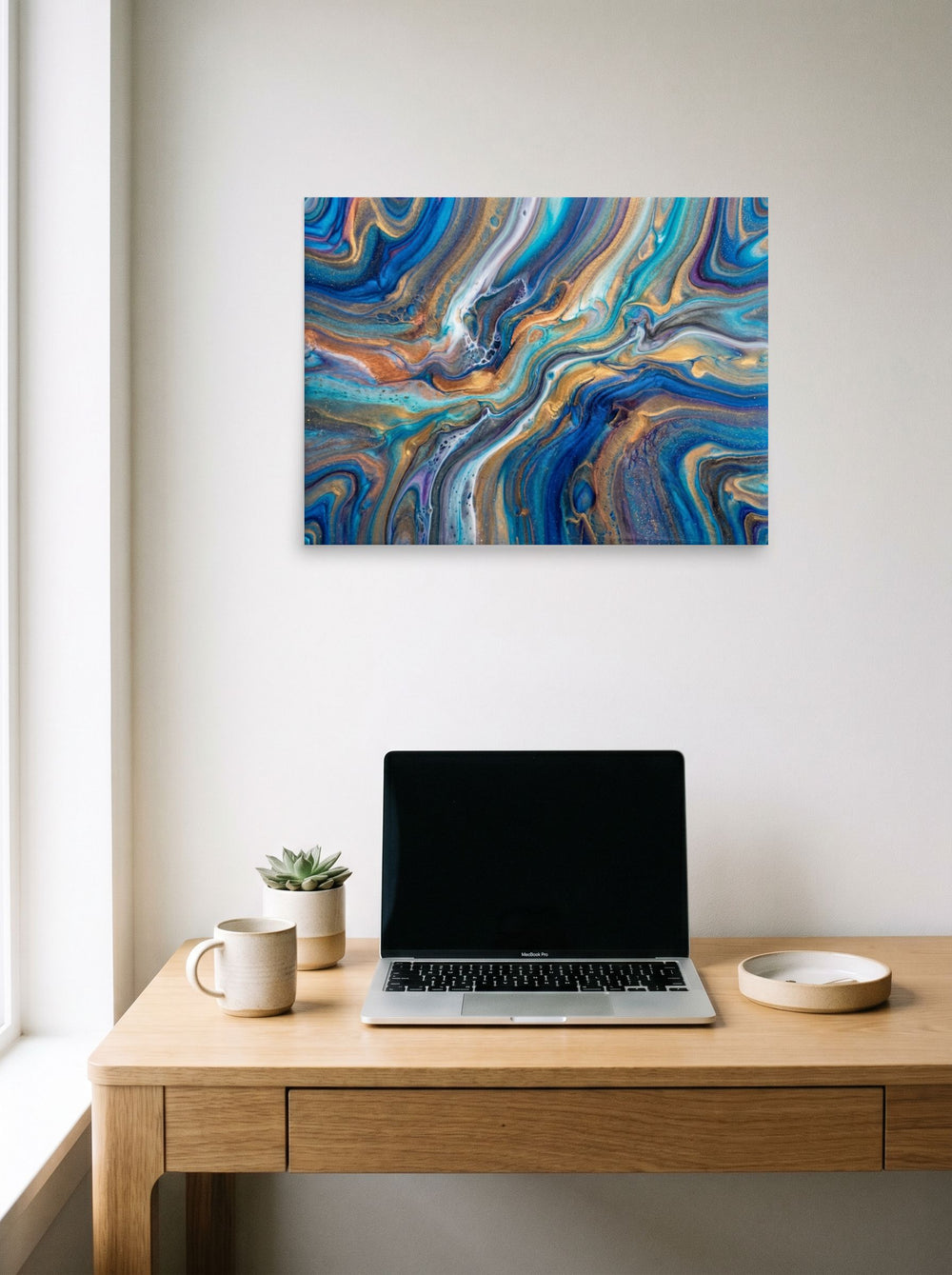 A 24x18 inch unframed paper Abstract art print of 'Sapphire Waves' hanging above a worktable with a laptop.