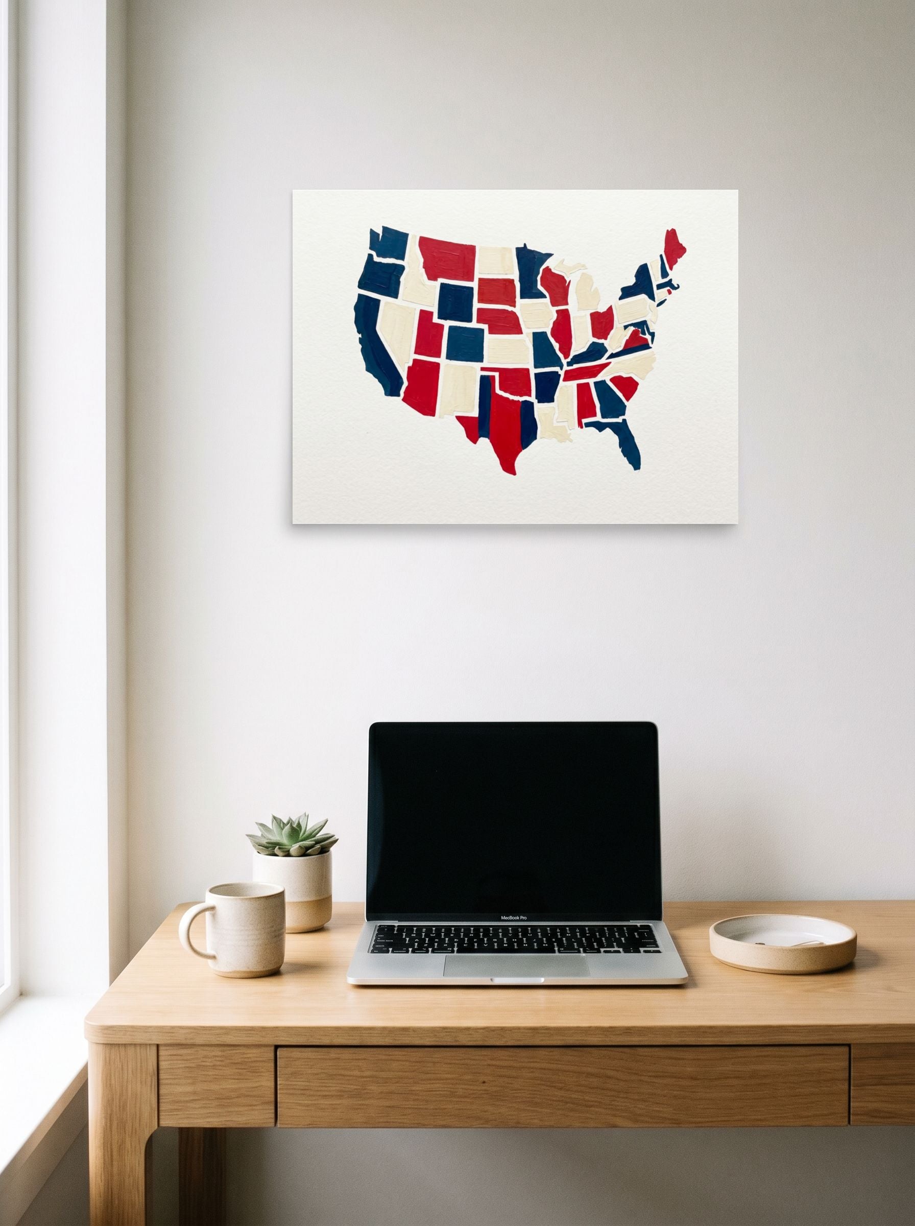 A 24x18 inch unframed paper Abstract art,Pop art print of 'The Patchwork States' hanging above a worktable with a laptop.