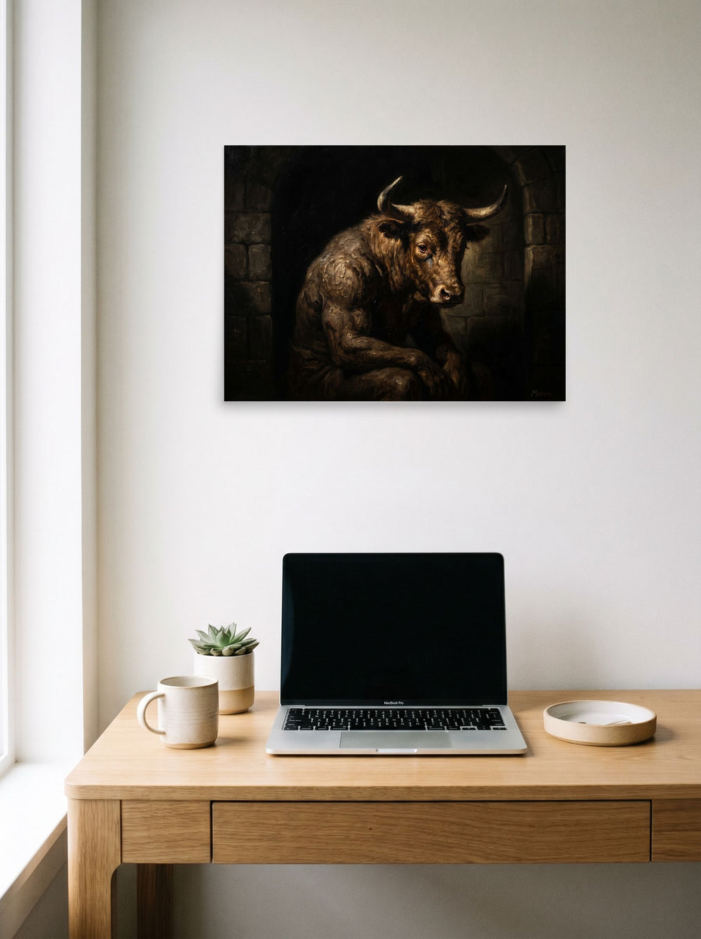 A 24x18 inch unframed paper Figurative art,Expressionism print of 'The Captive Beast' hanging above a worktable with a laptop.