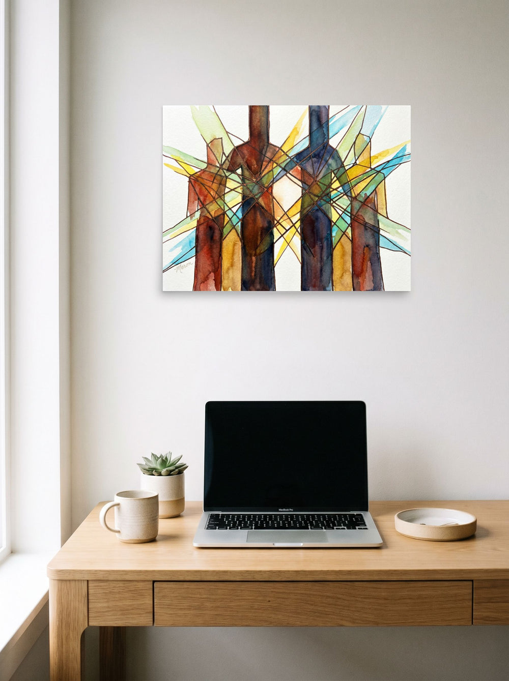 A 24x18 inch unframed paper Cubism print of 'Family Structure' hanging above a worktable with a laptop.