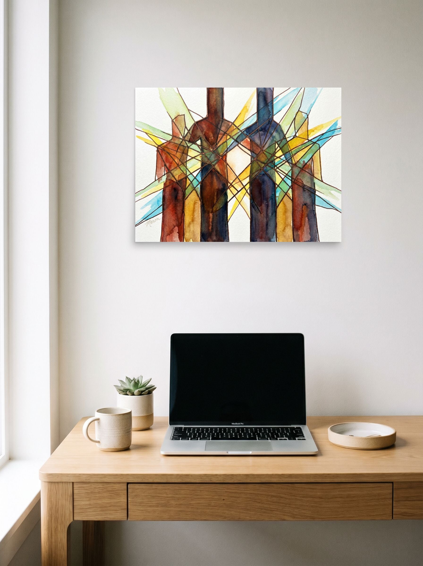 A 24x18 inch unframed paper Cubism print of 'Family Structure' hanging above a worktable with a laptop.