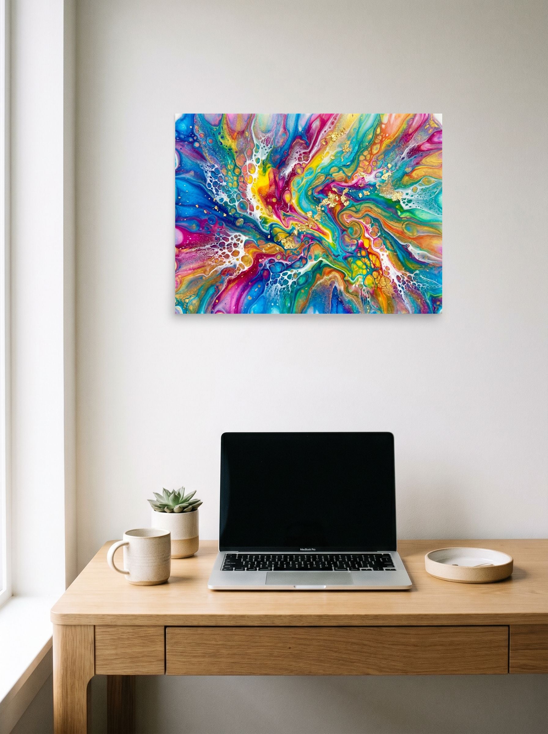 A 24x18 inch unframed paper Abstract art print of 'Rainbow Burst' hanging above a worktable with a laptop.