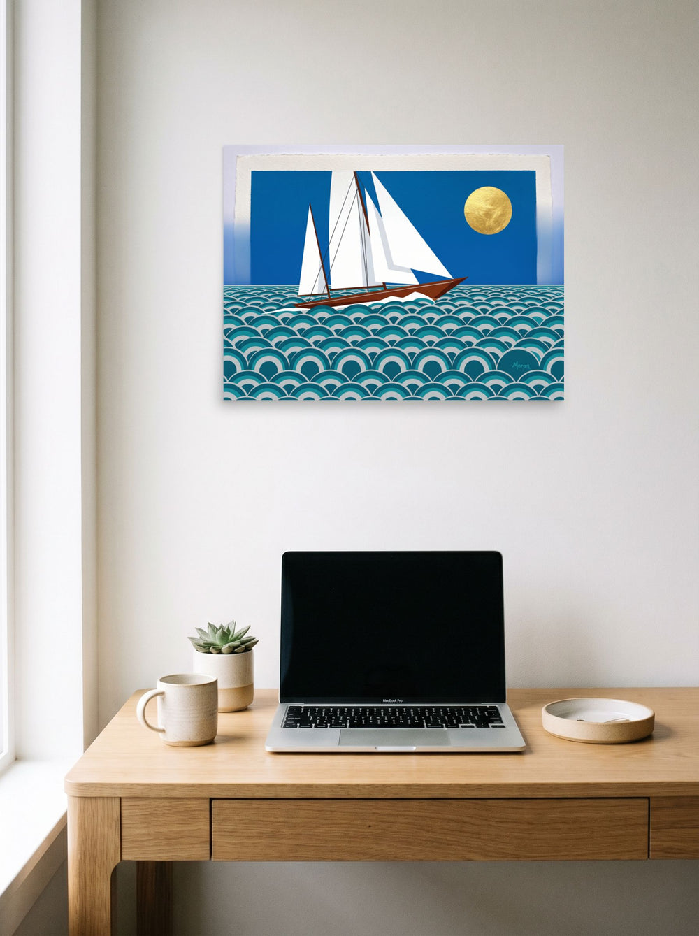 A 24x18 inch unframed paper Art Deco print of 'The Deco Voyage' hanging above a worktable with a laptop.