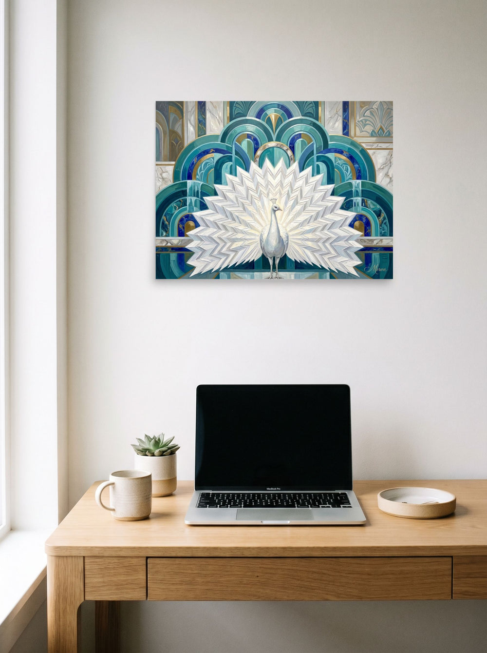 A 24x18 inch unframed paper Art Deco print of 'The Gilded Peacock' hanging above a worktable with a laptop.
