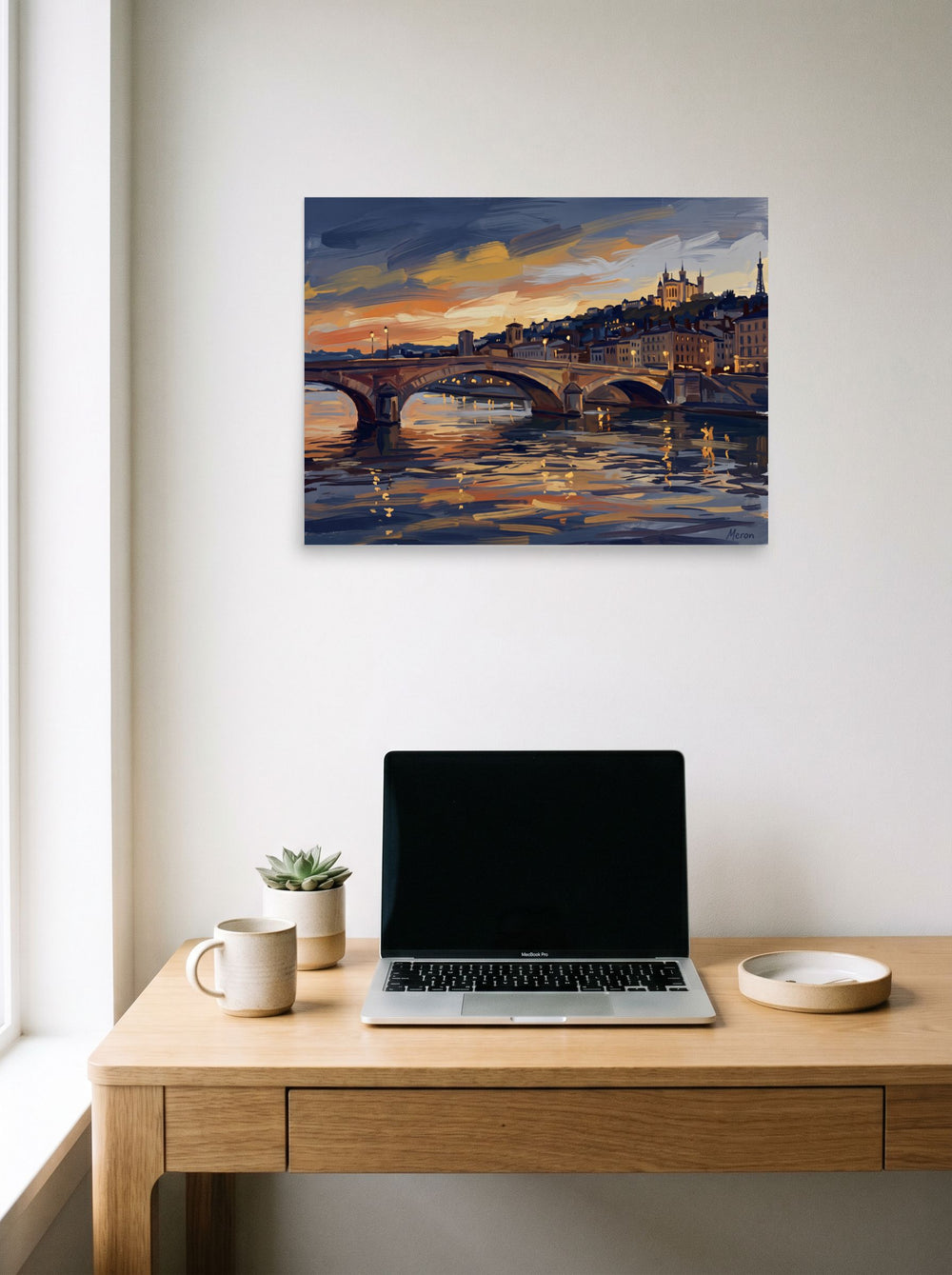 A 24x18 inch unframed paper Impressionism print of 'Dusk Over Lyon' hanging above a worktable with a laptop.