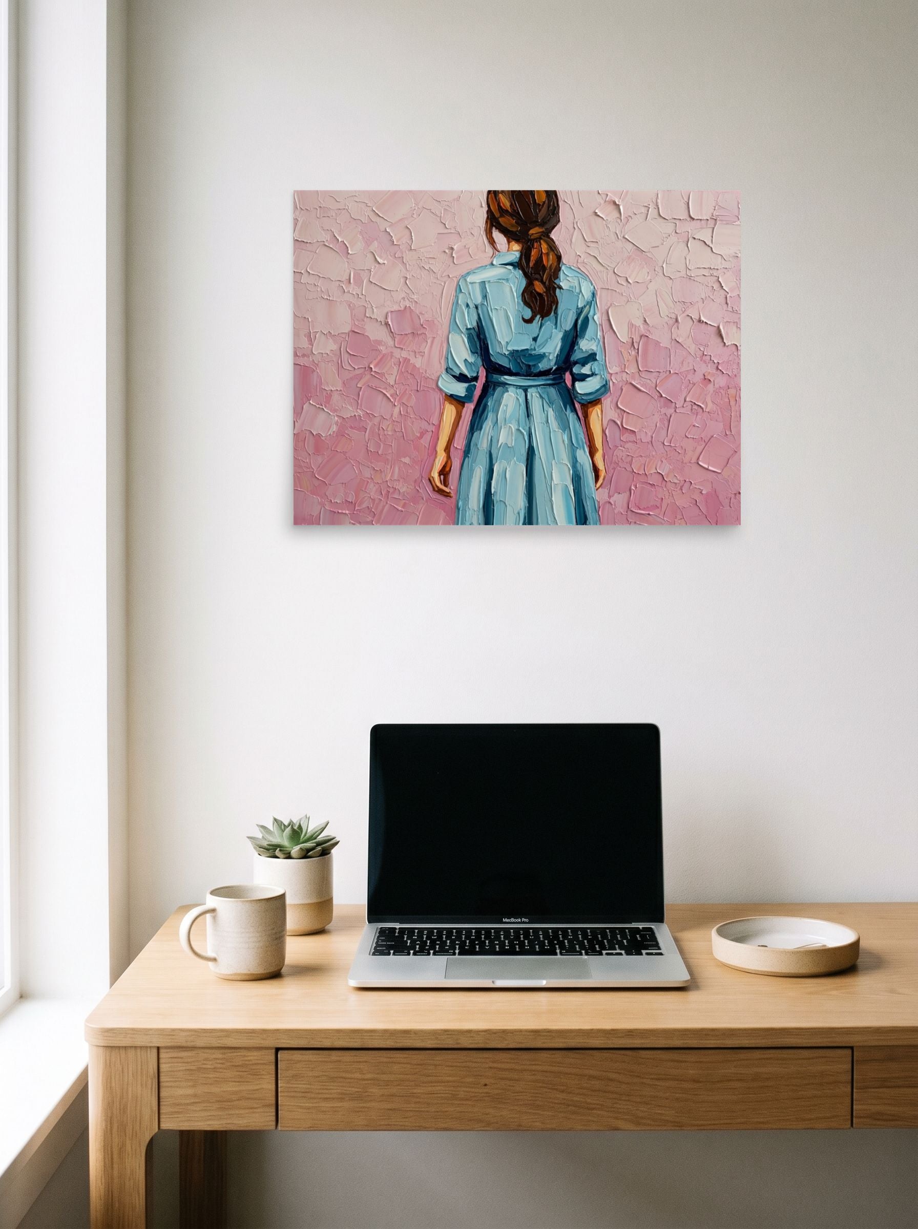 A 24x18 inch unframed paper Figurative art print of 'The Blue Dress' hanging above a worktable with a laptop.