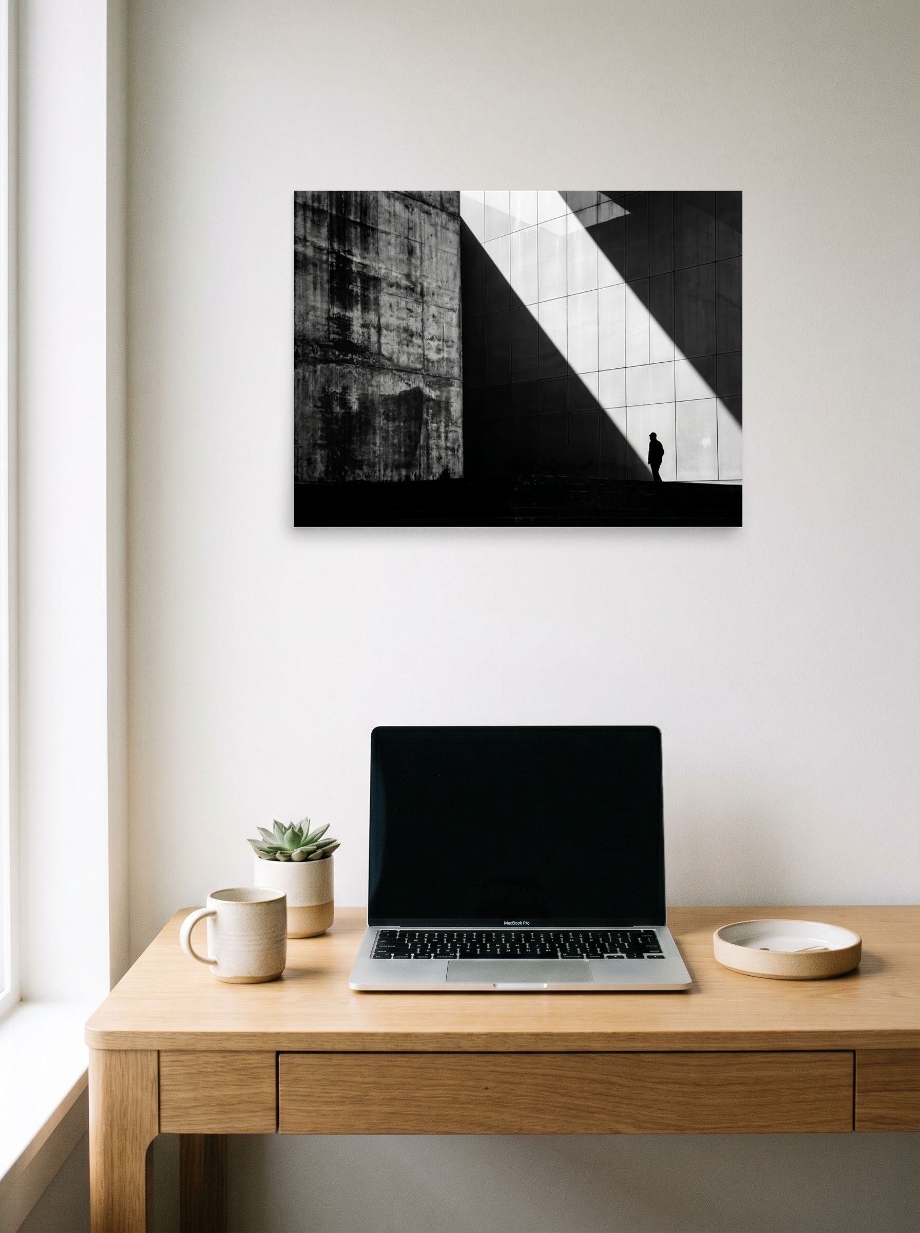 A 24x18 inch unframed paper Modernism print of 'Urban Geometry' hanging above a worktable with a laptop.