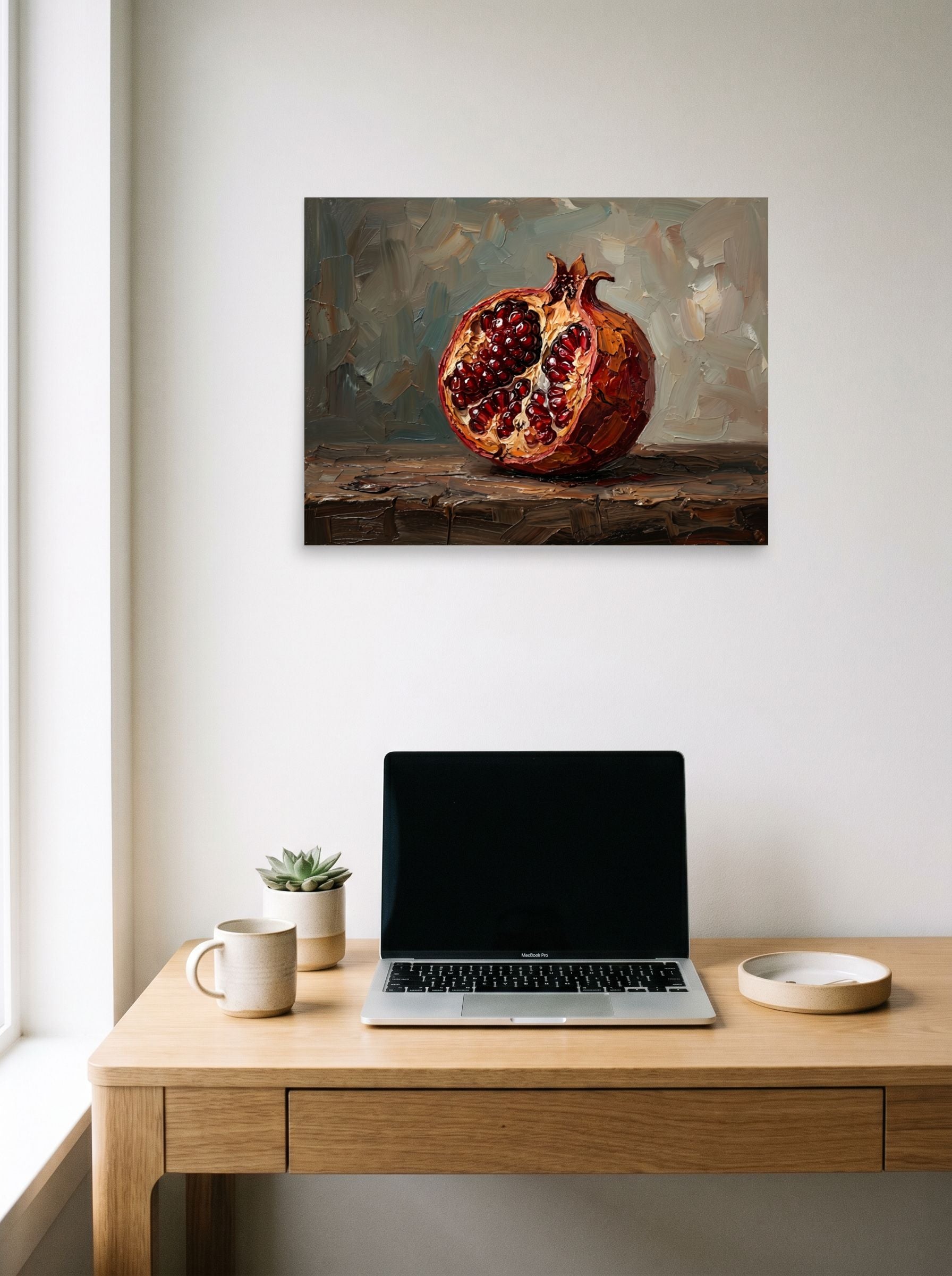 A 24x18 inch unframed paper Realism print of 'The Open Pomegranate' hanging above a worktable with a laptop.