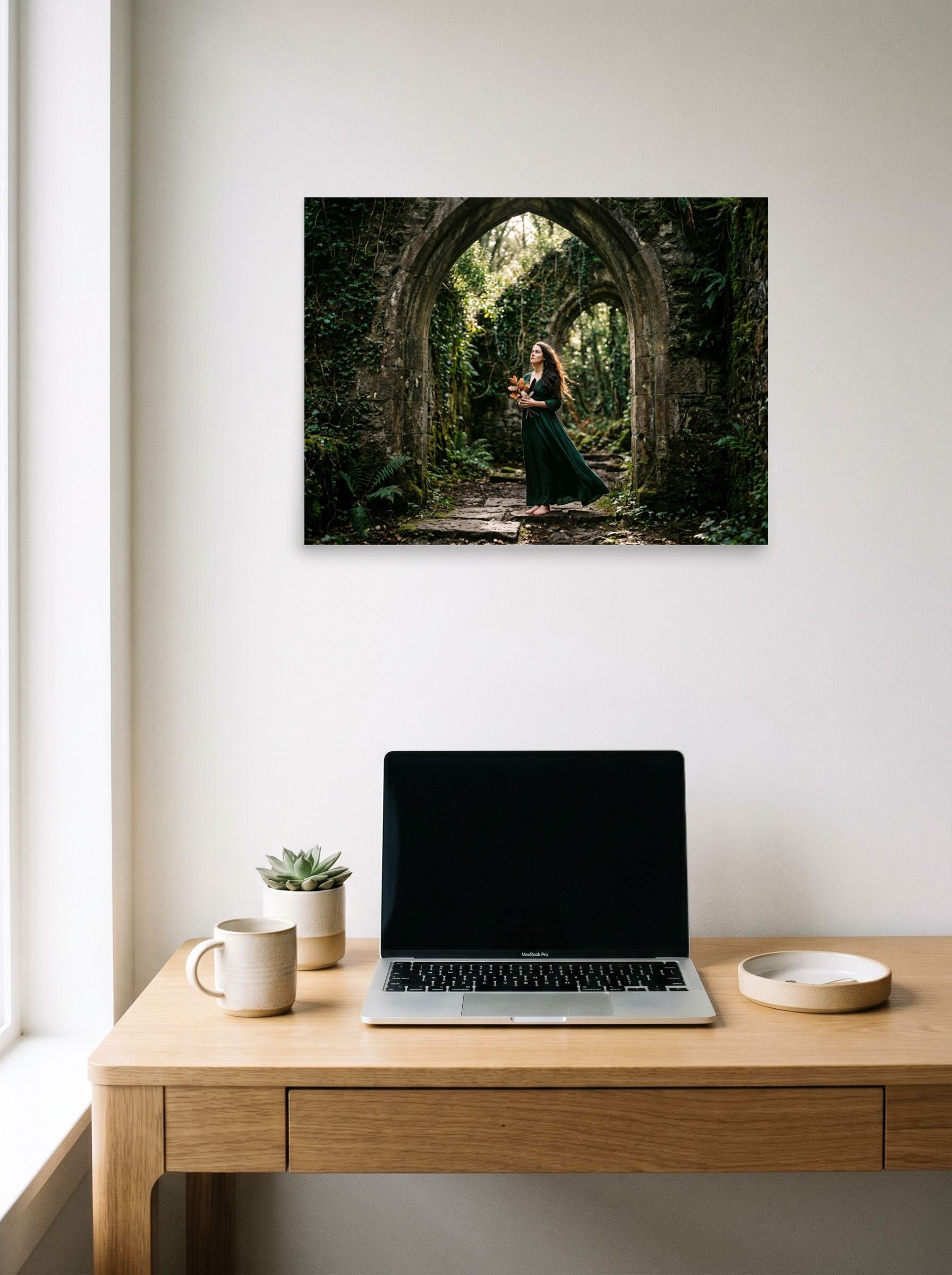 A 24x18 inch unframed paper Art photography print of 'The Forest Guardian' hanging above a worktable with a laptop.