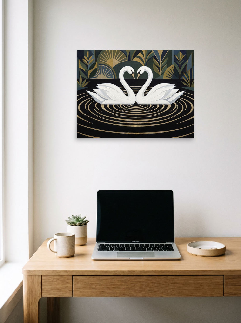 A 24x18 inch unframed paper Art Deco print of 'Deco Swans' hanging above a worktable with a laptop.