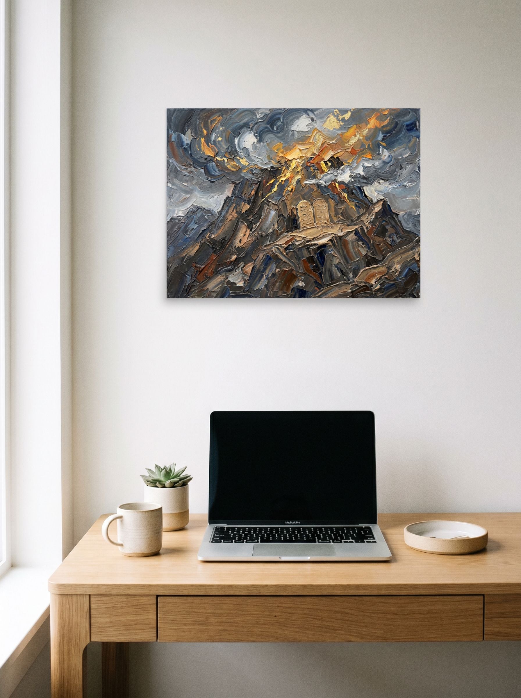 A 24x18 inch unframed paper Symbolism print of 'The Covenant on Sinai' hanging above a worktable with a laptop.