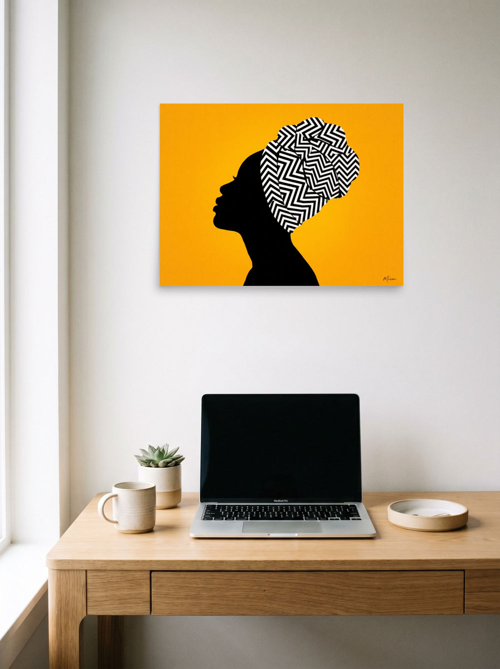 A 24x18 inch unframed paper Afrofuturism,Pop art print of 'Geometric Crown' hanging above a worktable with a laptop.