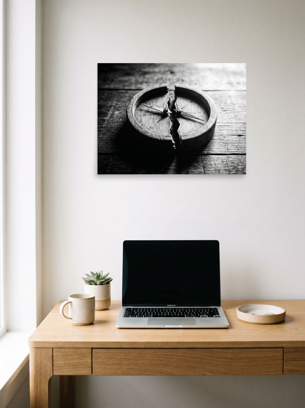 A 24x18 inch unframed paper Art photography print of 'Lost Direction' hanging above a worktable with a laptop.