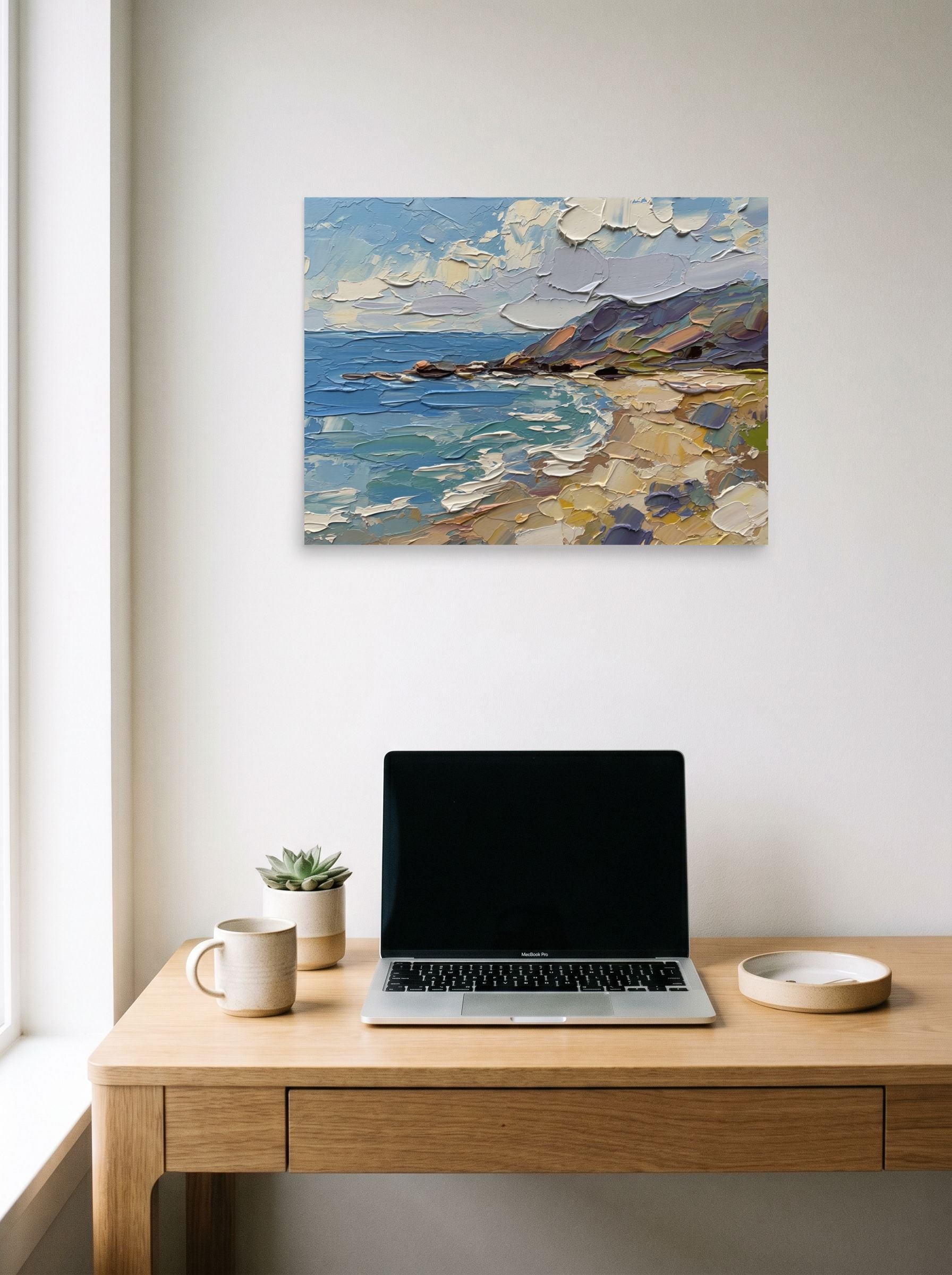 A 24x18 inch unframed paper Impressionism print of 'Impasto Coastline' hanging above a worktable with a laptop.