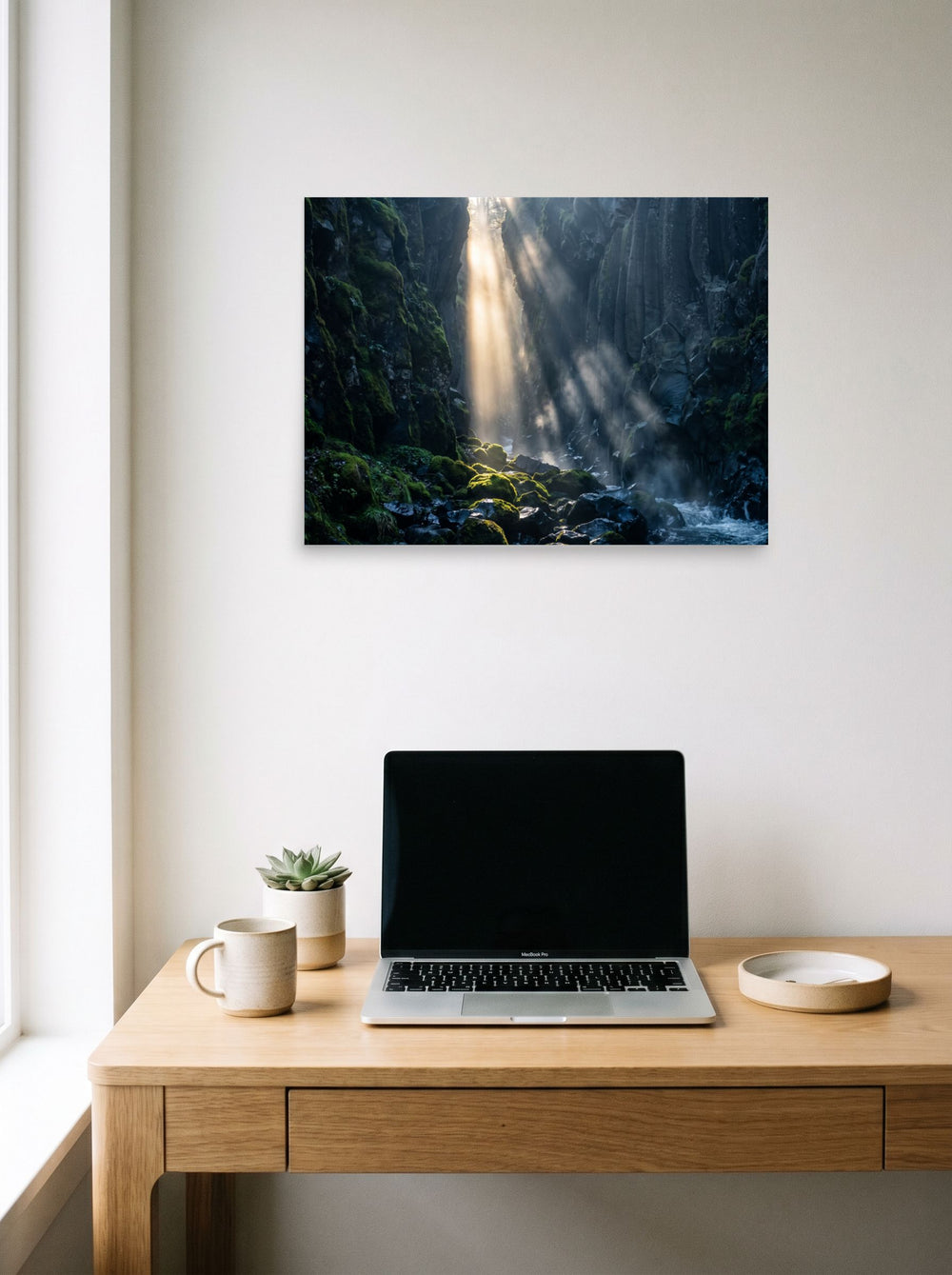 A 24x18 inch unframed paper Art photography print of 'Sunbeams in the Gorge' hanging above a worktable with a laptop.