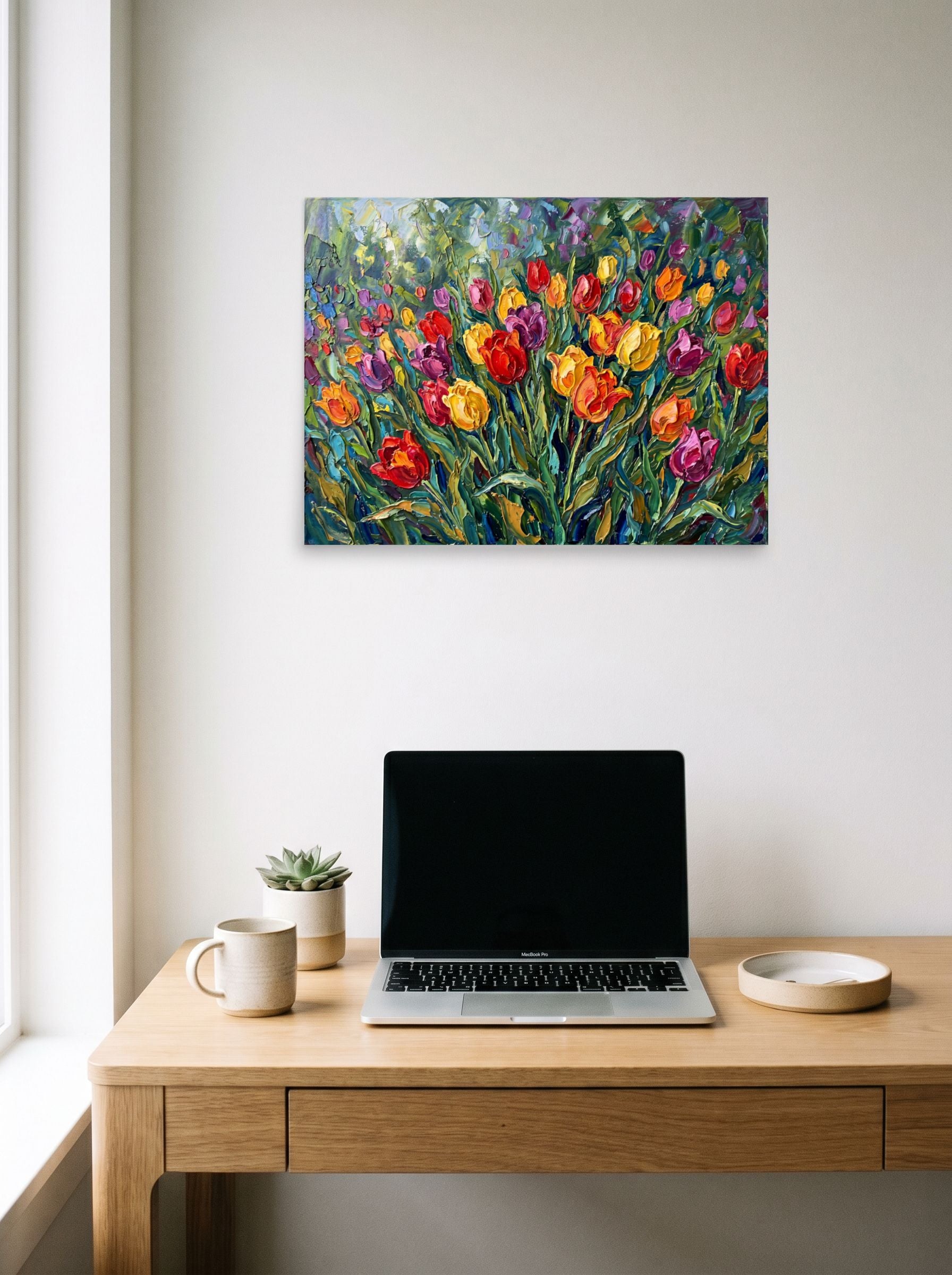 A 24x18 inch unframed paper Impressionism print of 'Tulip Symphony' hanging above a worktable with a laptop.