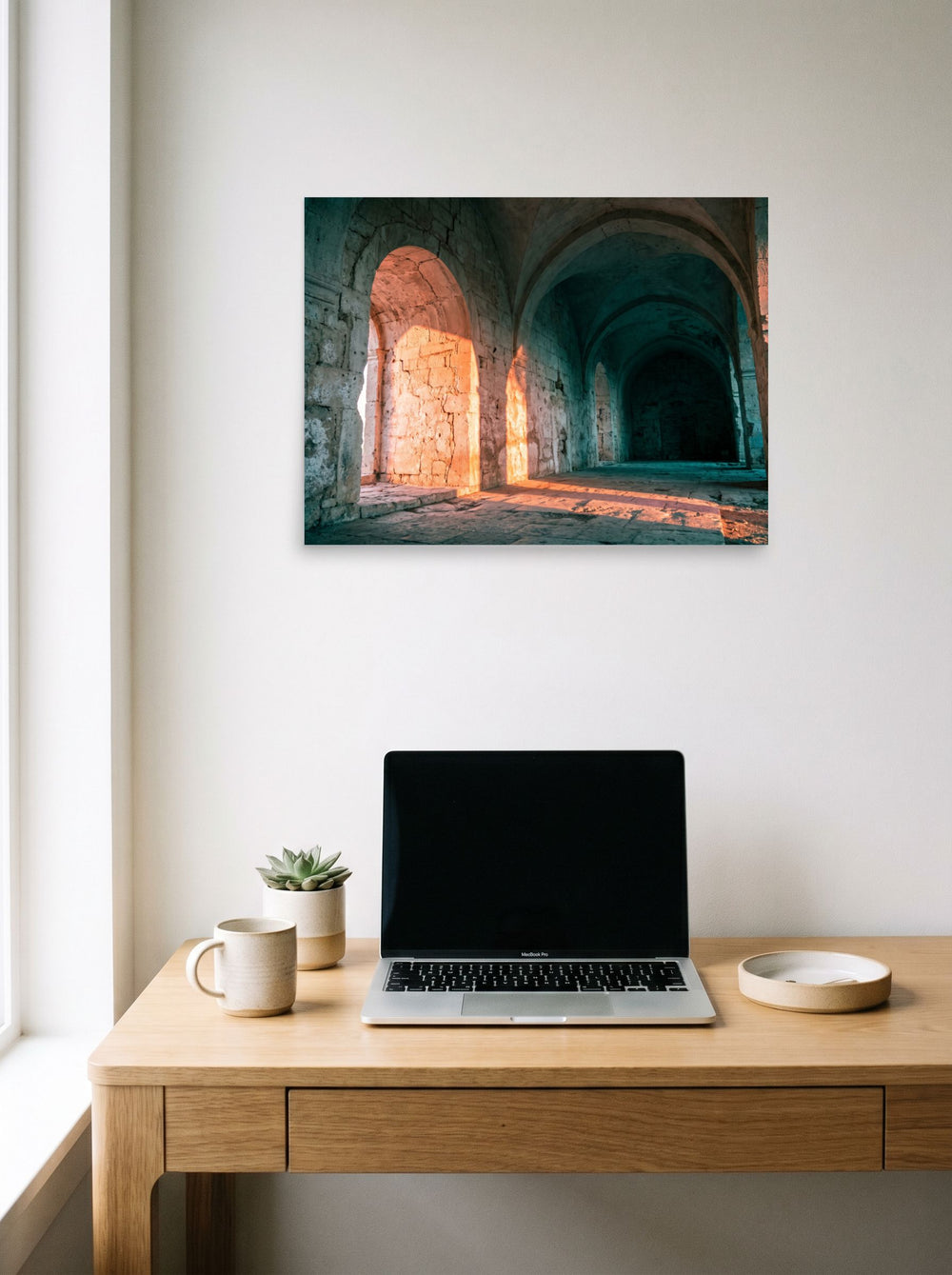 A 24x18 inch unframed paper Art photography print of 'Arches at Sunset' hanging above a worktable with a laptop.
