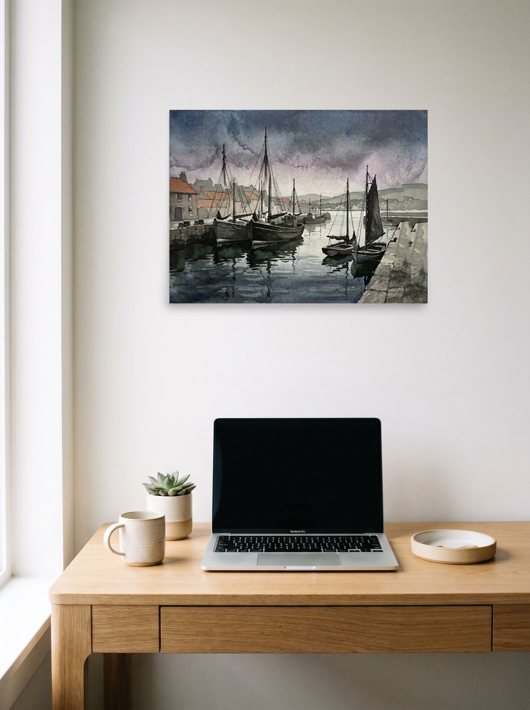 A 24x18 inch unframed paper Realism print of 'Harbor at Dusk' hanging above a worktable with a laptop.