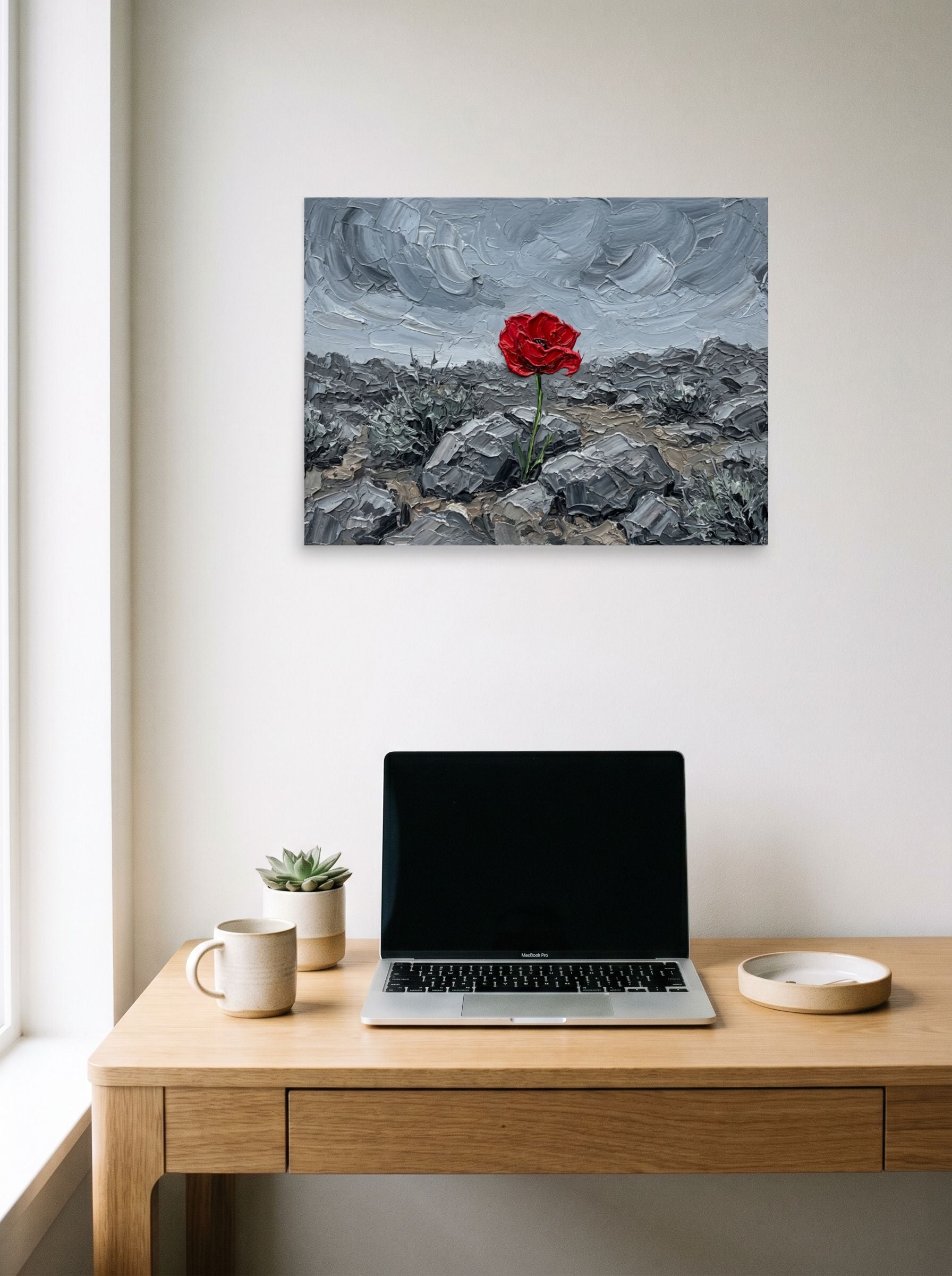 A 24x18 inch unframed paper Symbolism print of 'Resilience in Stone' hanging above a worktable with a laptop.