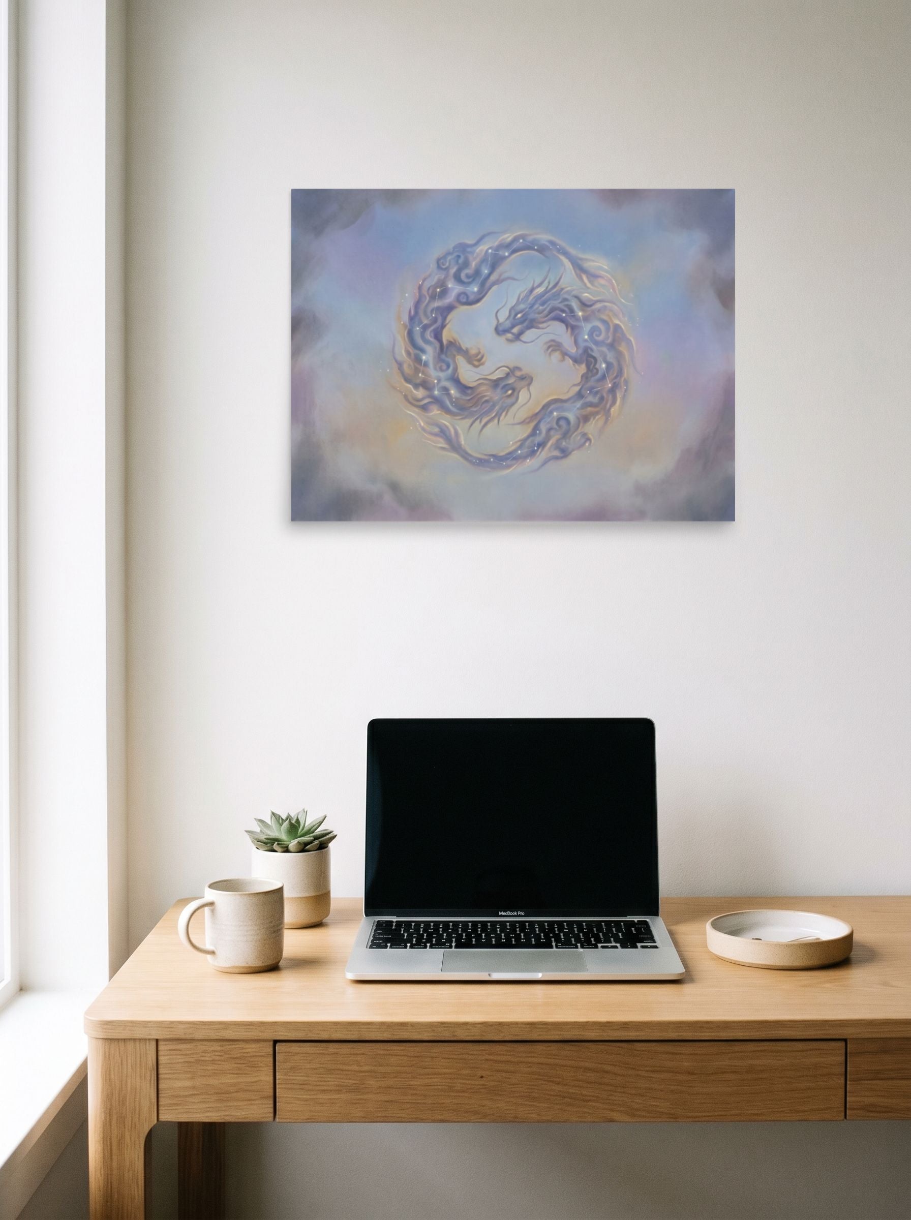 A 24x18 inch unframed paper Surrealism print of 'Celestial Dragons' hanging above a worktable with a laptop.