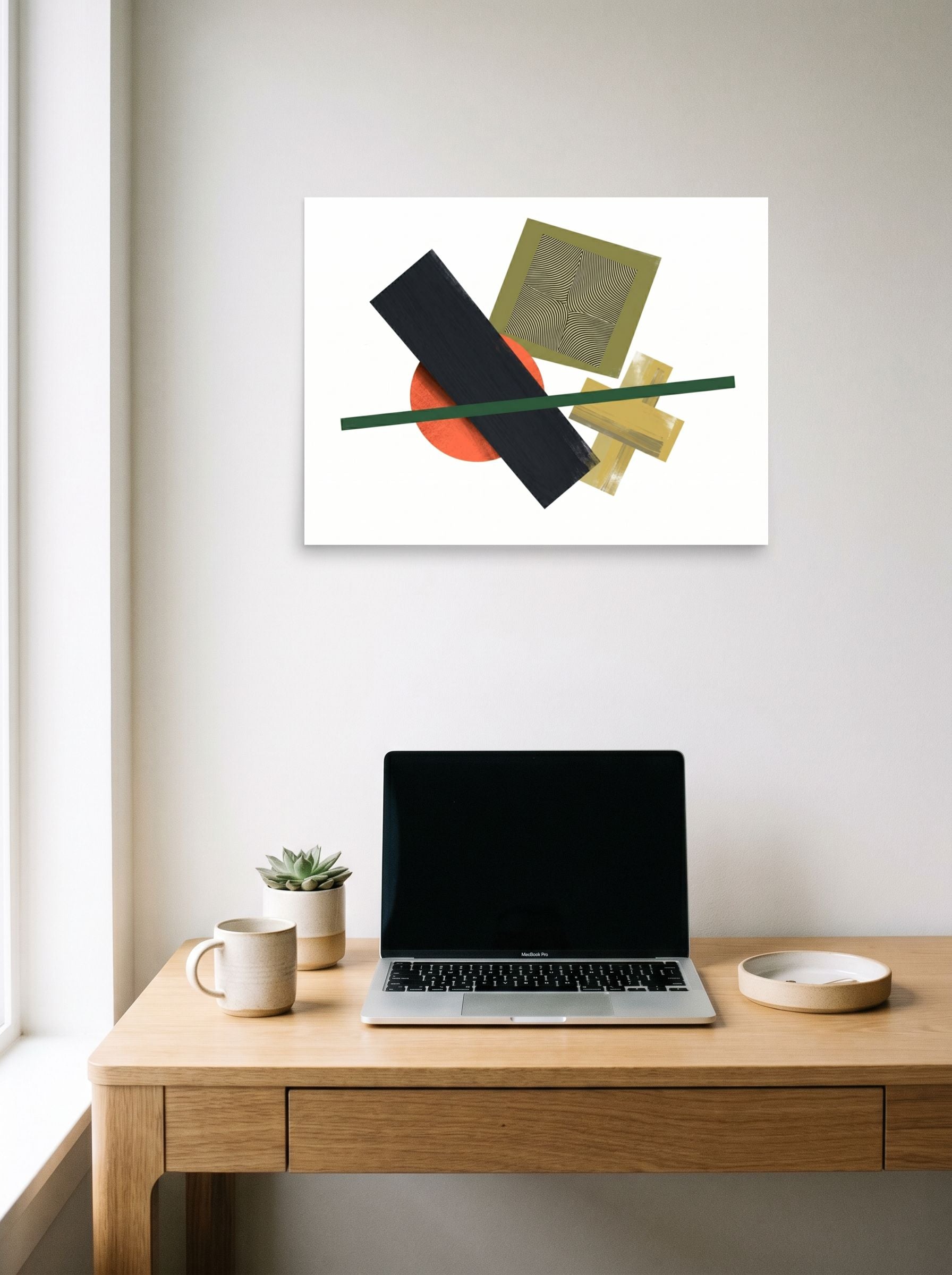 A 24x18 inch unframed paper Suprematism print of 'The Geometry of Sound' hanging above a worktable with a laptop.