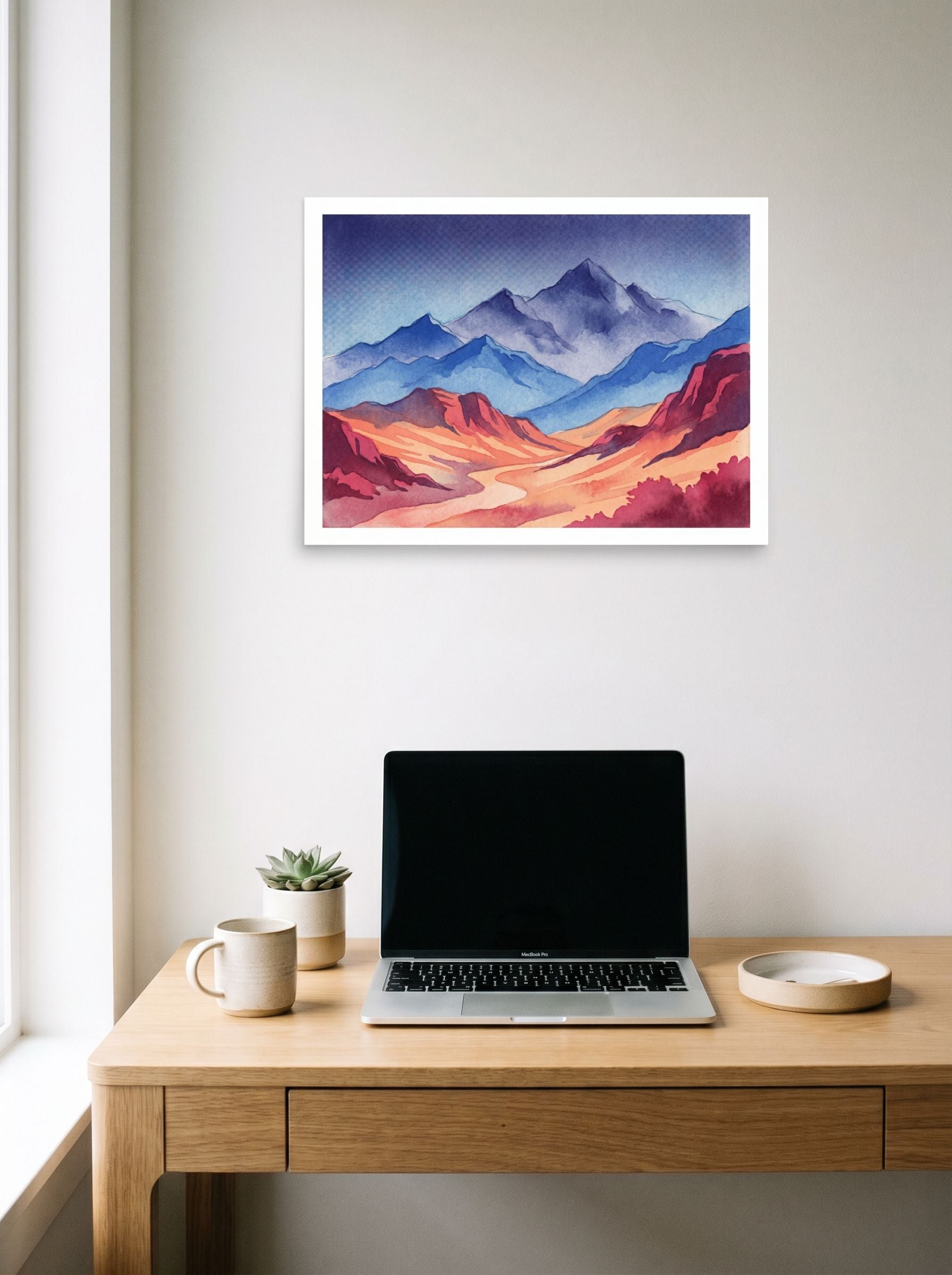 A 24x18 inch unframed paper Realism print of 'Mountain Dawn' hanging above a worktable with a laptop.