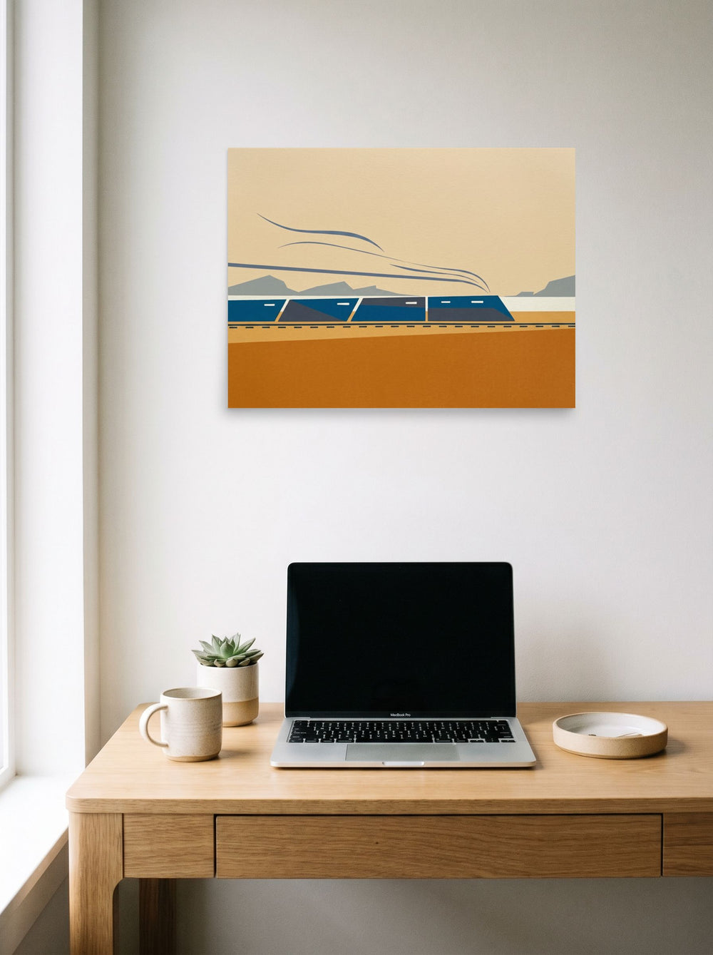 A 24x18 inch unframed paper Minimalism print of 'The Coastal Express' hanging above a worktable with a laptop.