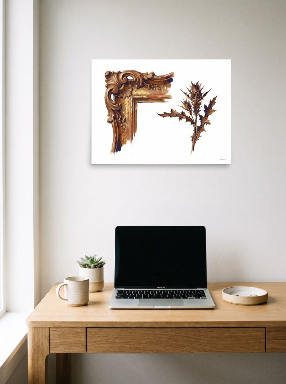 A 24x18 inch unframed paper Baroque,Realism print of 'Gilded Frame and Thistle' hanging above a worktable with a laptop.