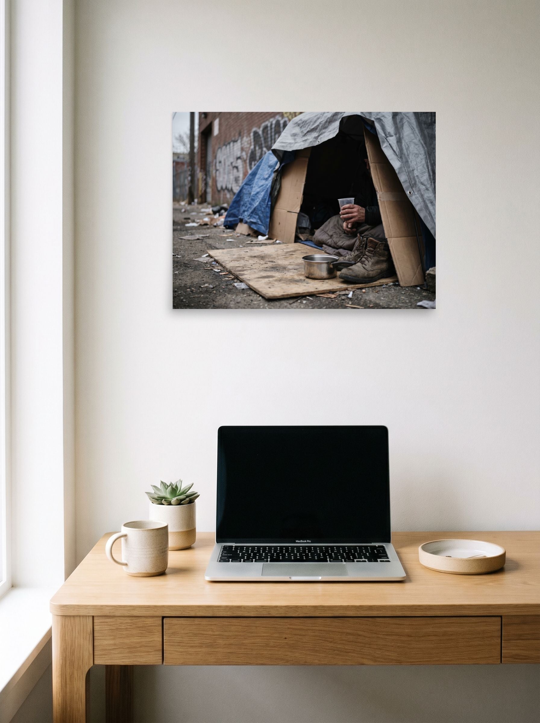 A 24x18 inch unframed paper Art photography print of 'Urban Realities' hanging above a worktable with a laptop.
