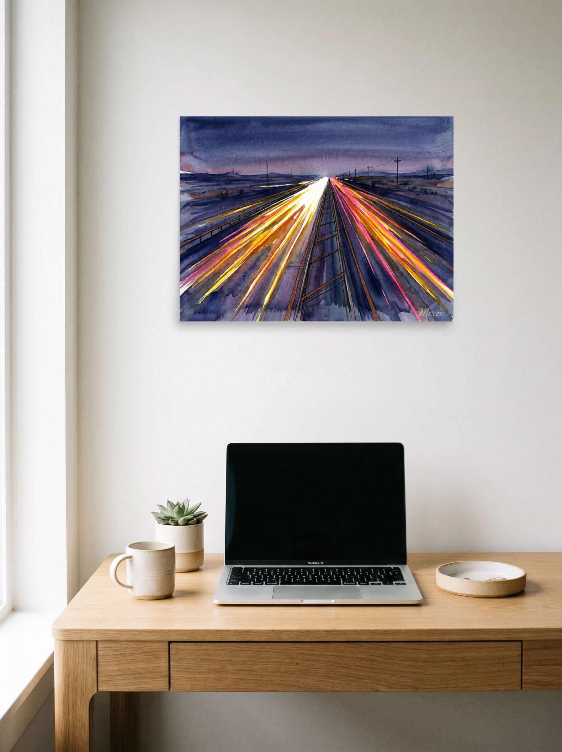 A 24x18 inch unframed paper Futurism print of 'The American Interstate' hanging above a worktable with a laptop.