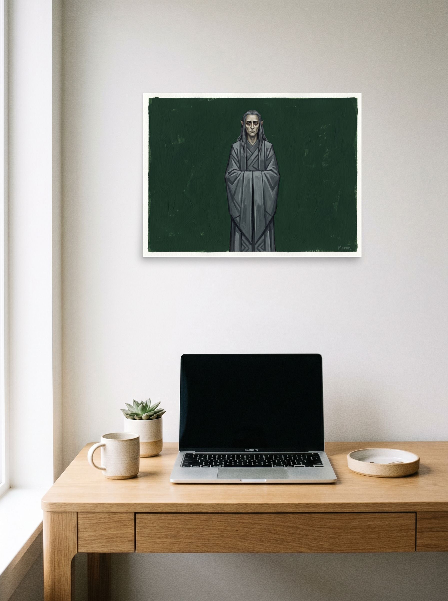 A 24x18 inch unframed paper Figurative art,Surrealism print of 'The Somber Elf' hanging above a worktable with a laptop.