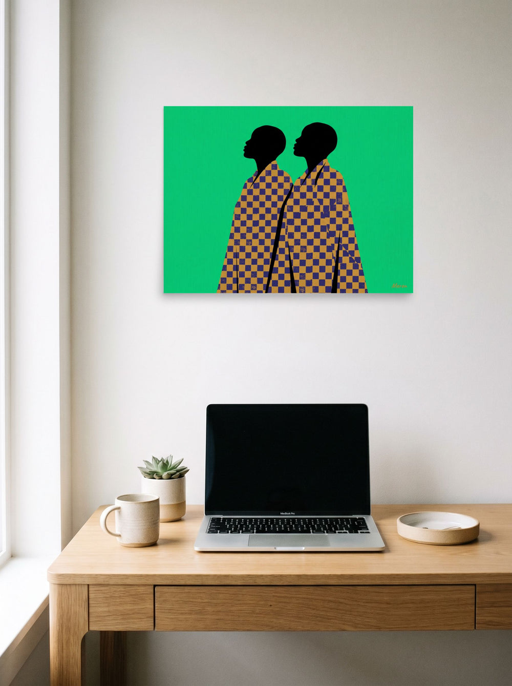 A 24x18 inch unframed paper Afrofuturism,Pop art print of 'Checkered Solidarity' hanging above a worktable with a laptop.