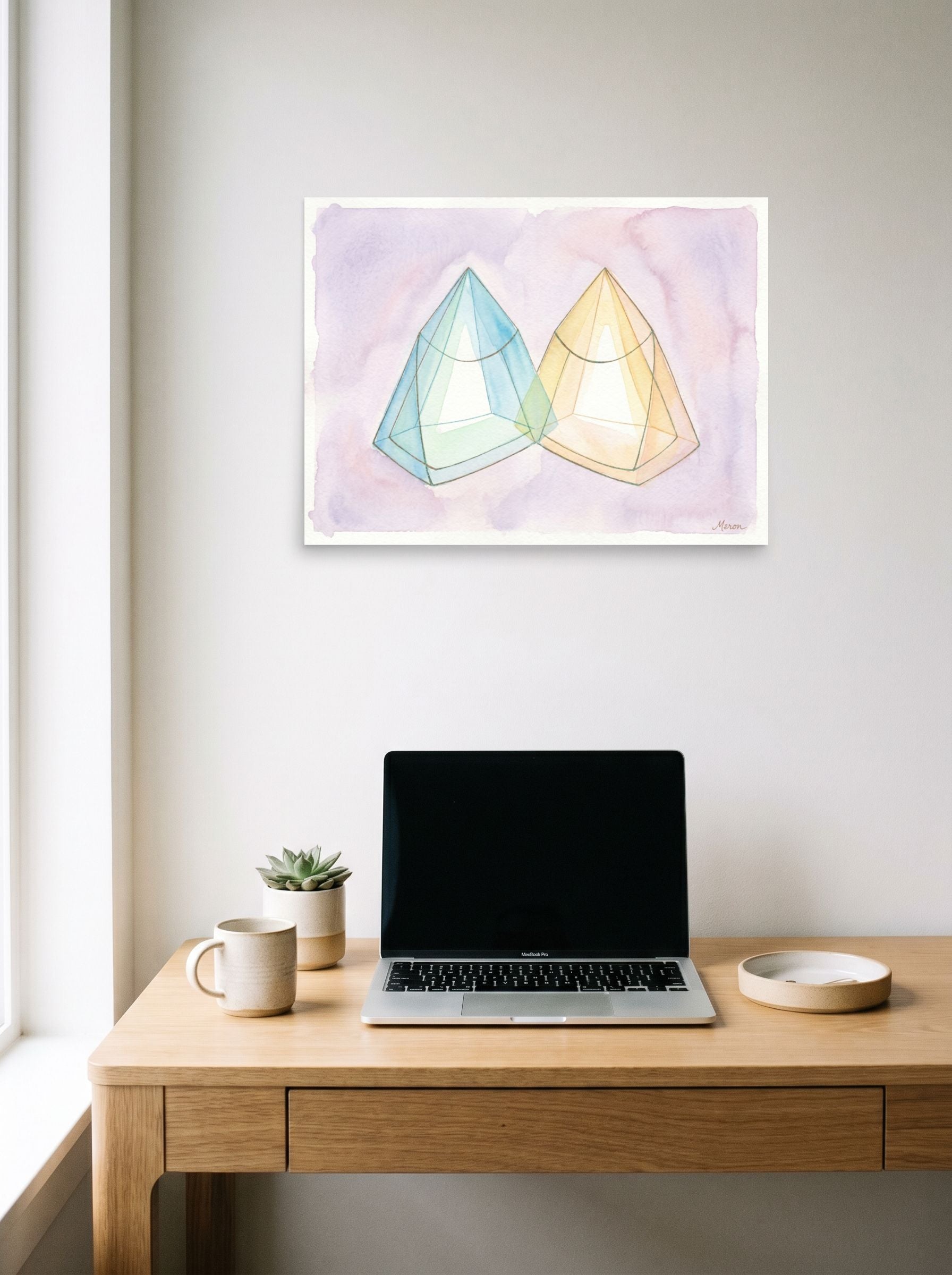A 24x18 inch unframed paper Geometric abstract art print of 'Twin Babies Diptych' hanging above a worktable with a laptop.