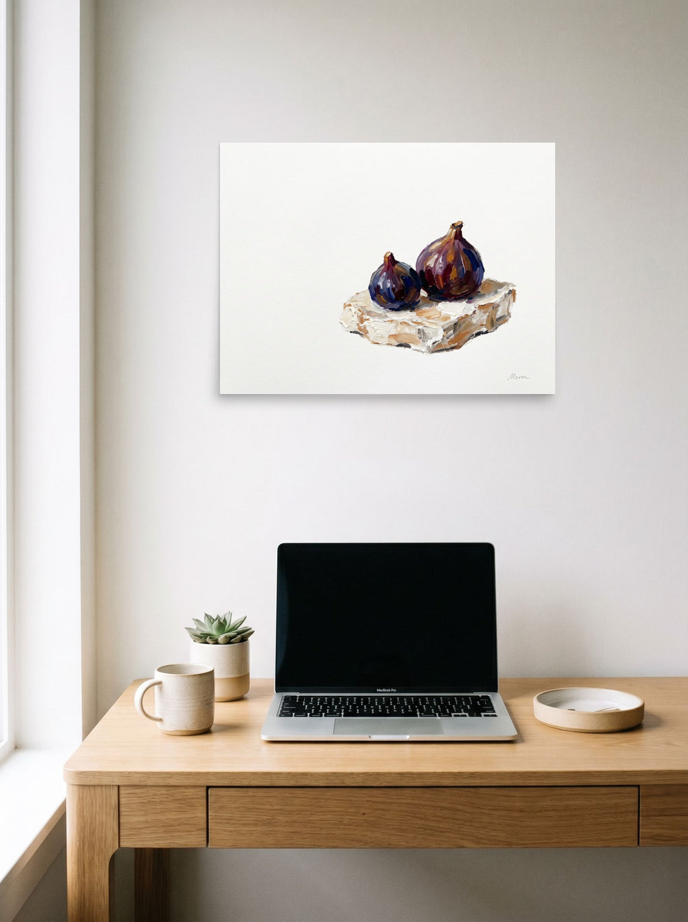 A 24x18 inch unframed paper Realism,Modernism print of 'Ripe Figs on Cream' hanging above a worktable with a laptop.