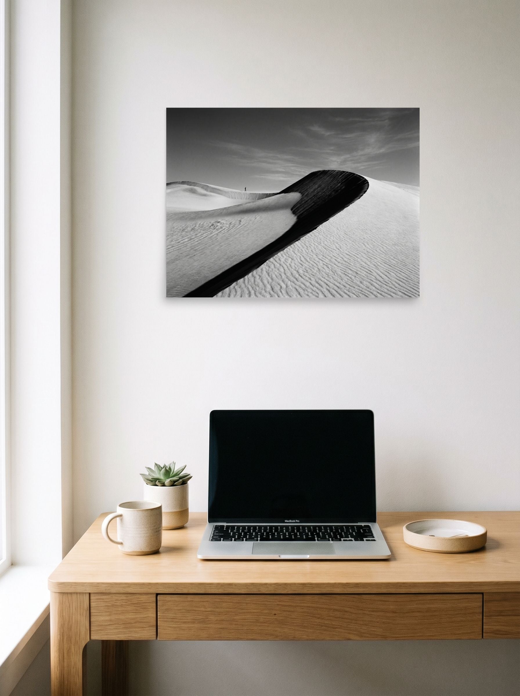 A 24x18 inch unframed paper Art photography print of 'Footsteps in the Void' hanging above a worktable with a laptop.
