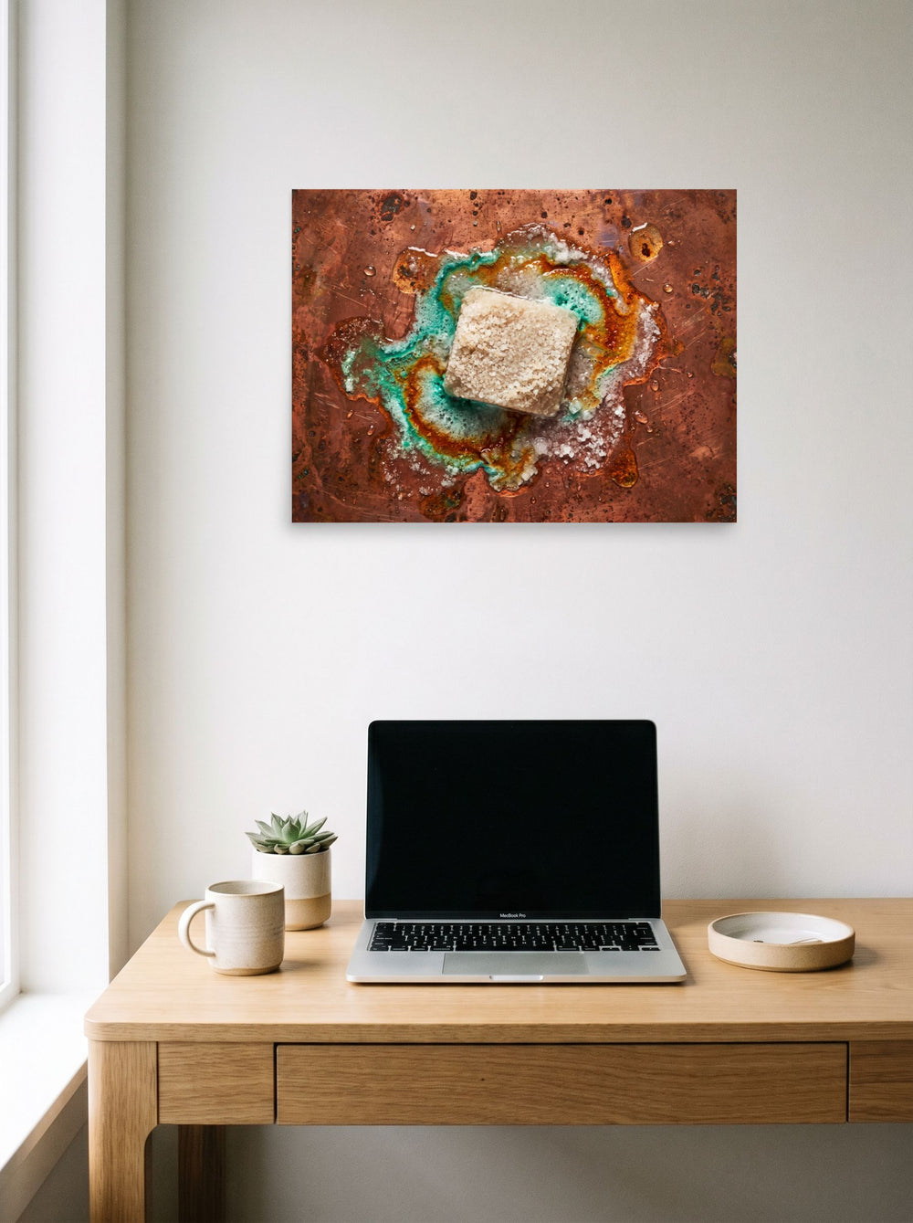 A 24x18 inch unframed paper Art photography print of 'Alchemy of Verdigris' hanging above a worktable with a laptop.