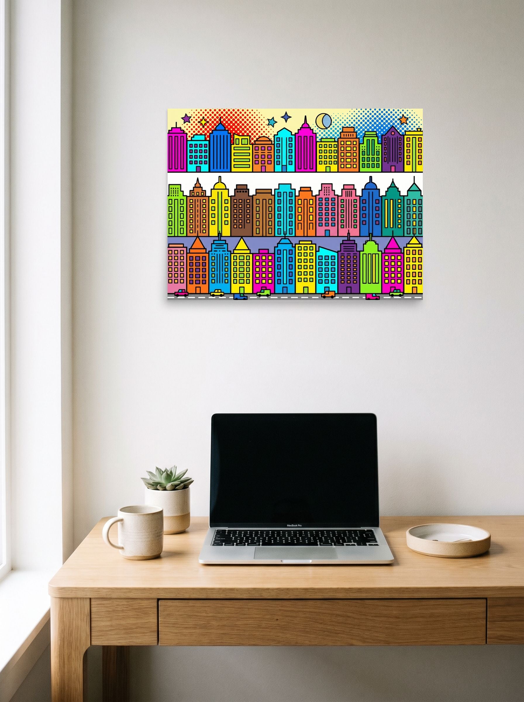 A 24x18 inch unframed paper Pop art print of 'Bright City Blocks' hanging above a worktable with a laptop.