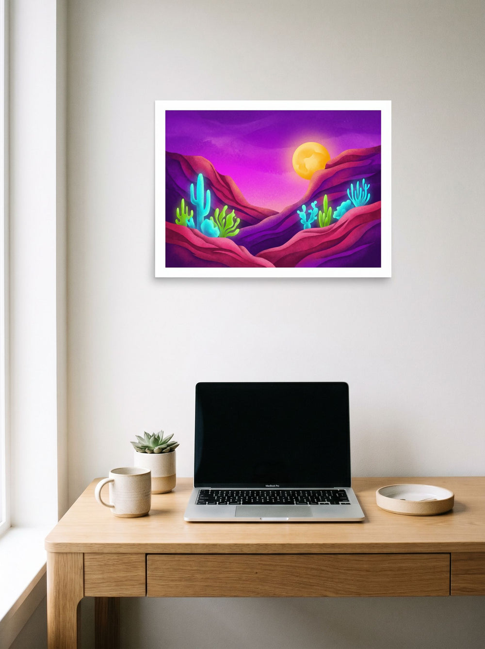 A 24x18 inch unframed paper Surrealism,Psychedelic art print of 'Bioluminescent Desert' hanging above a worktable with a laptop.