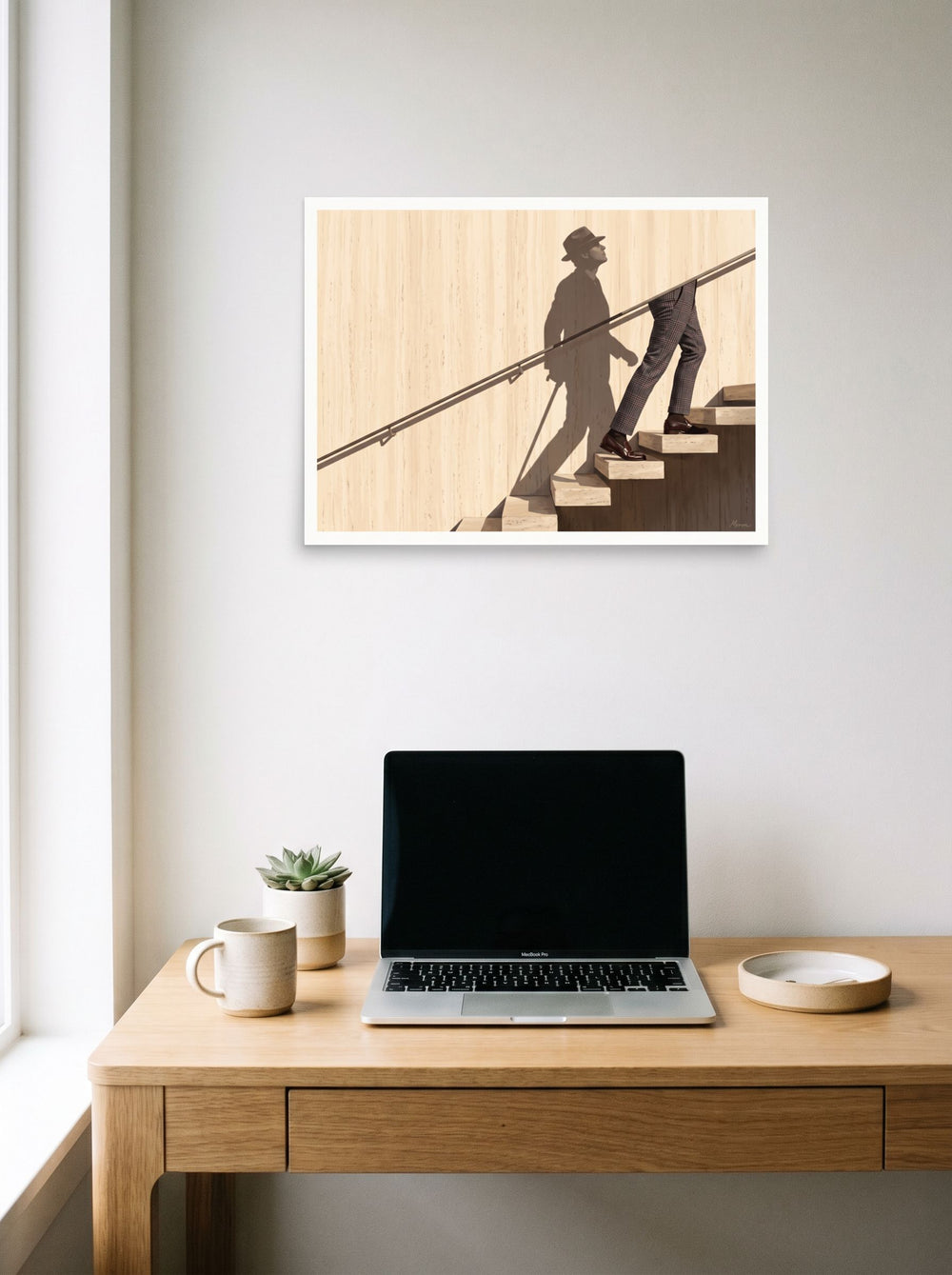A 24x18 inch unframed paper Surrealism,Realism print of 'Ascent of the Shadow' hanging above a worktable with a laptop.