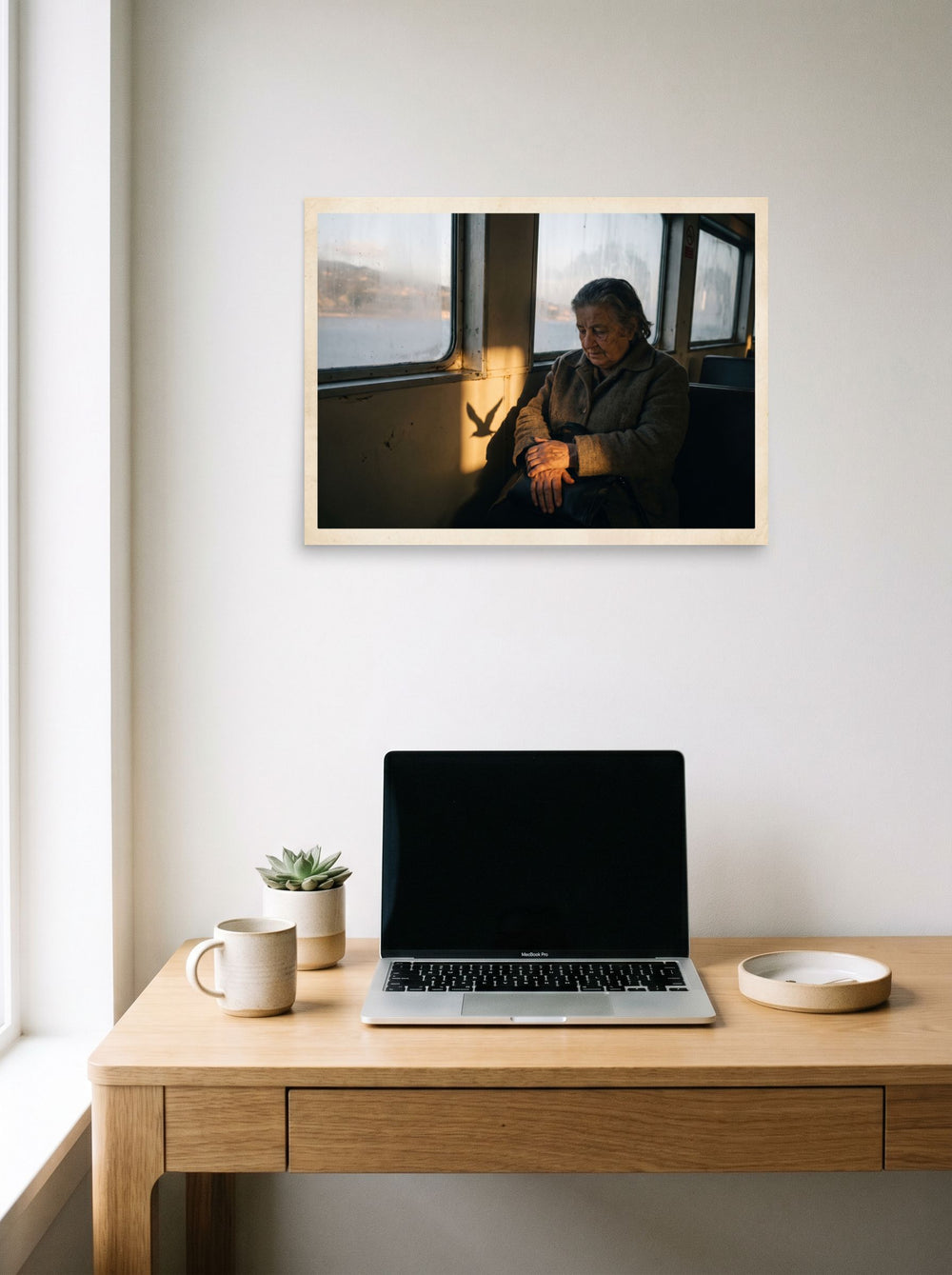 A 24x18 inch unframed paper Art photography print of 'Shadow of the Gull' hanging above a worktable with a laptop.