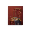 'Brass and Indigo' — a Realism,Modernism print. An oil painting still life featuring a golden trumpet on a wooden chair draped with a blue and gold geometric textile against a deep red wall, perfect for a music room or lounge.