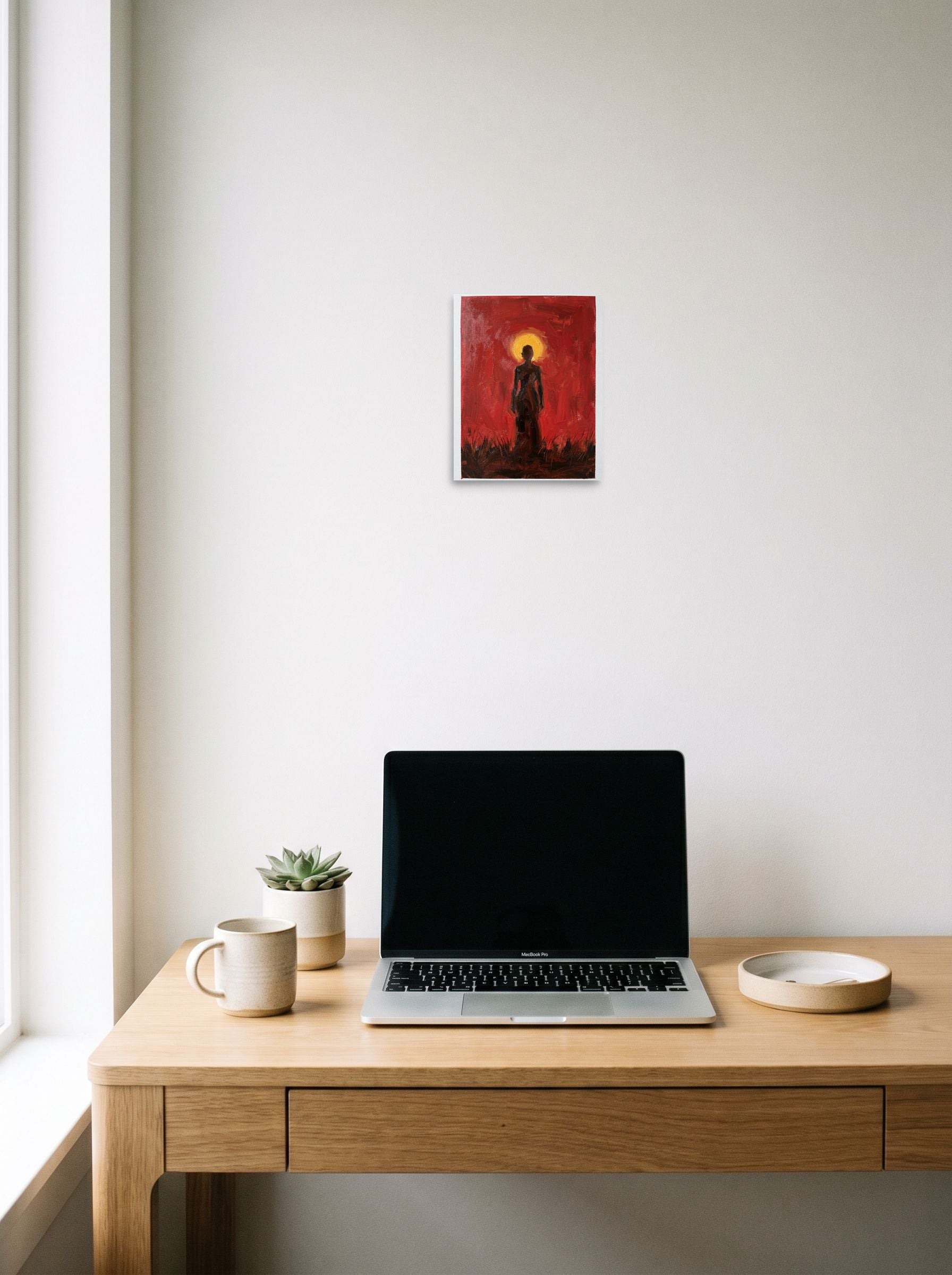 A 8x10 inch unframed paper Expressionism print of 'Crimson Halo' hanging above a worktable with a laptop.