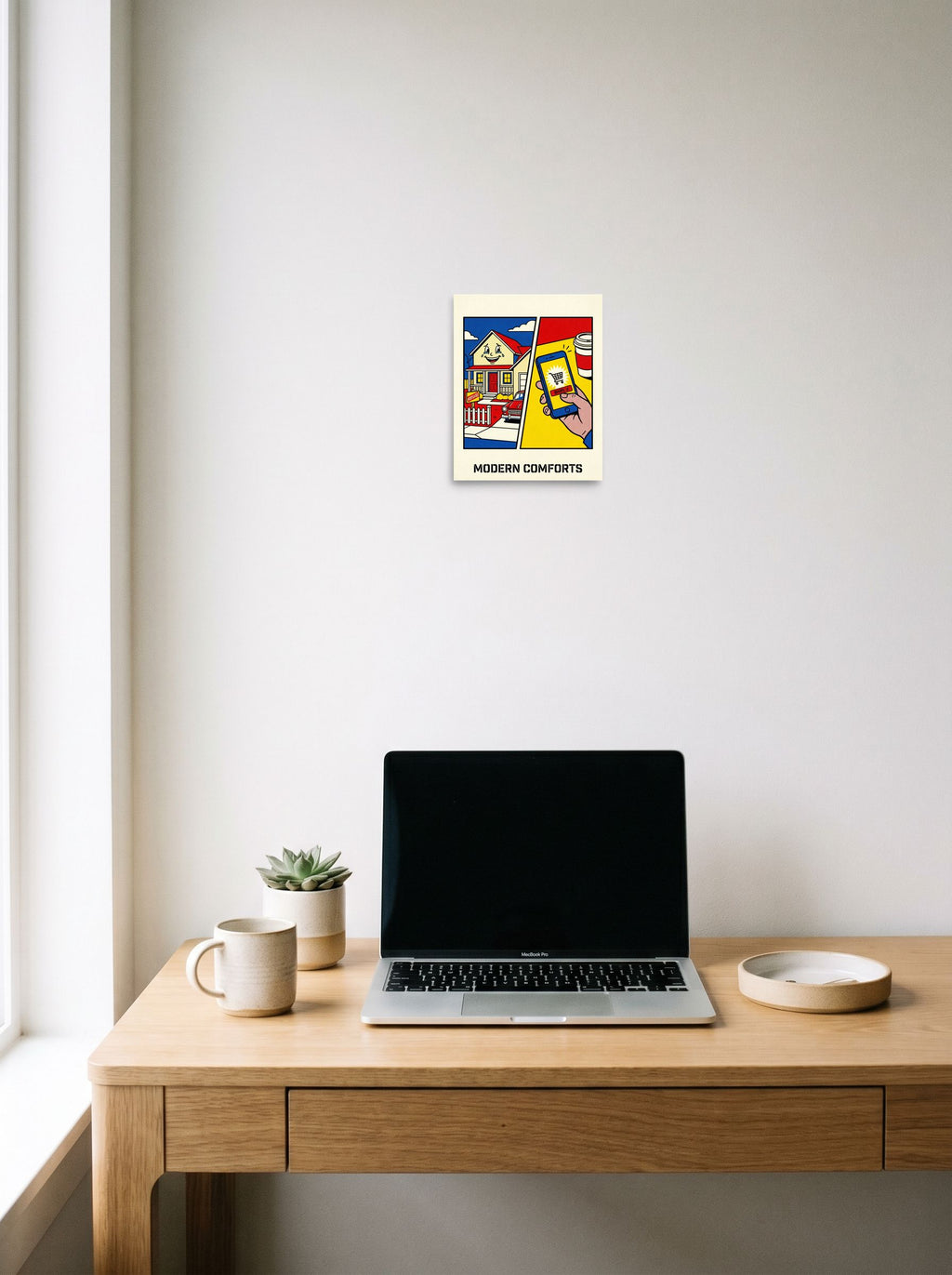 A 8x10 inch unframed paper Pop art print of 'Modern Comforts' hanging above a worktable with a laptop.