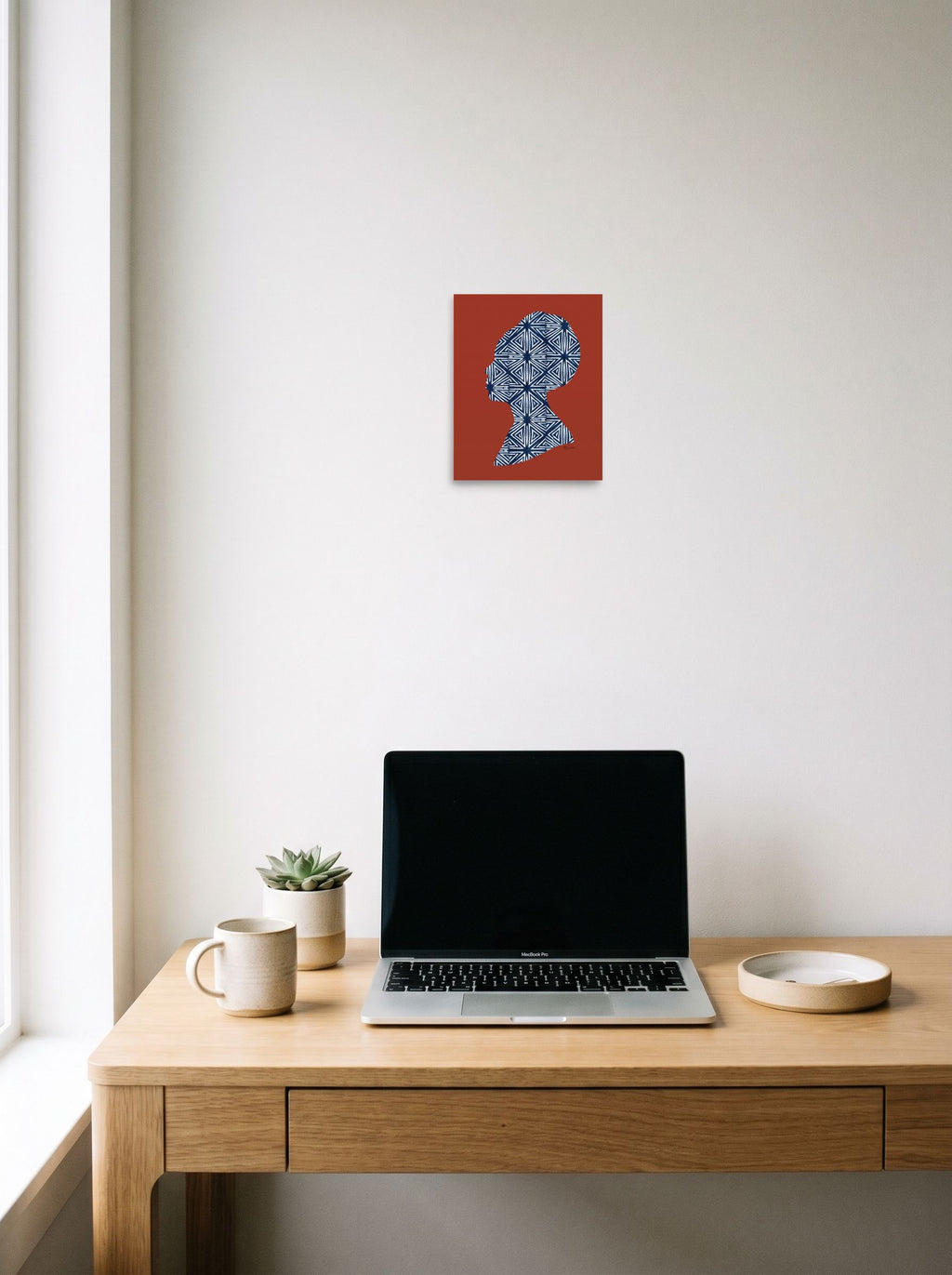 A 8x10 inch unframed paper Figurative art,Minimalism print of 'Indigo Heritage' hanging above a worktable with a laptop.