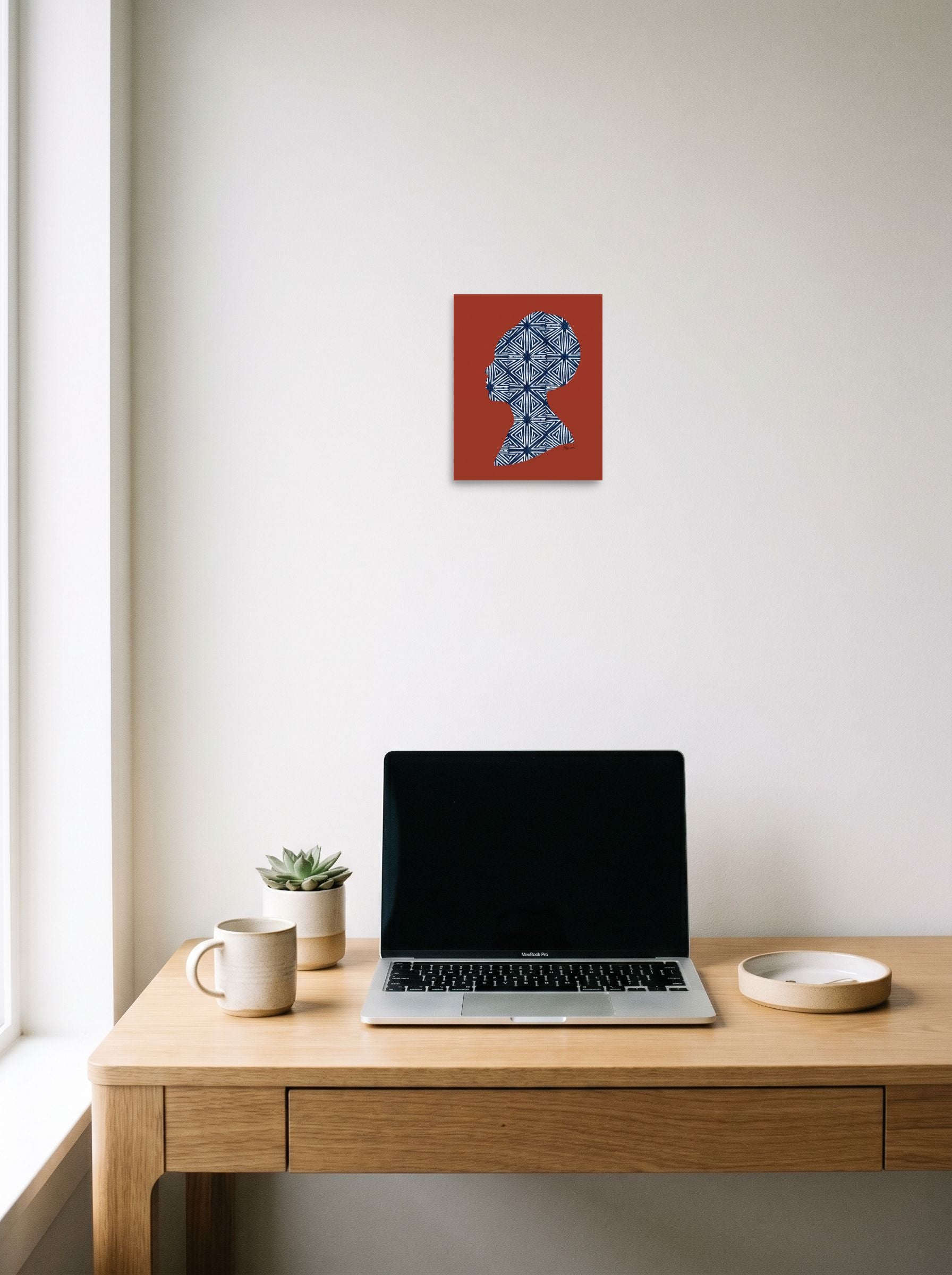 A 8x10 inch unframed paper Figurative art,Minimalism print of 'Indigo Heritage' hanging above a worktable with a laptop.