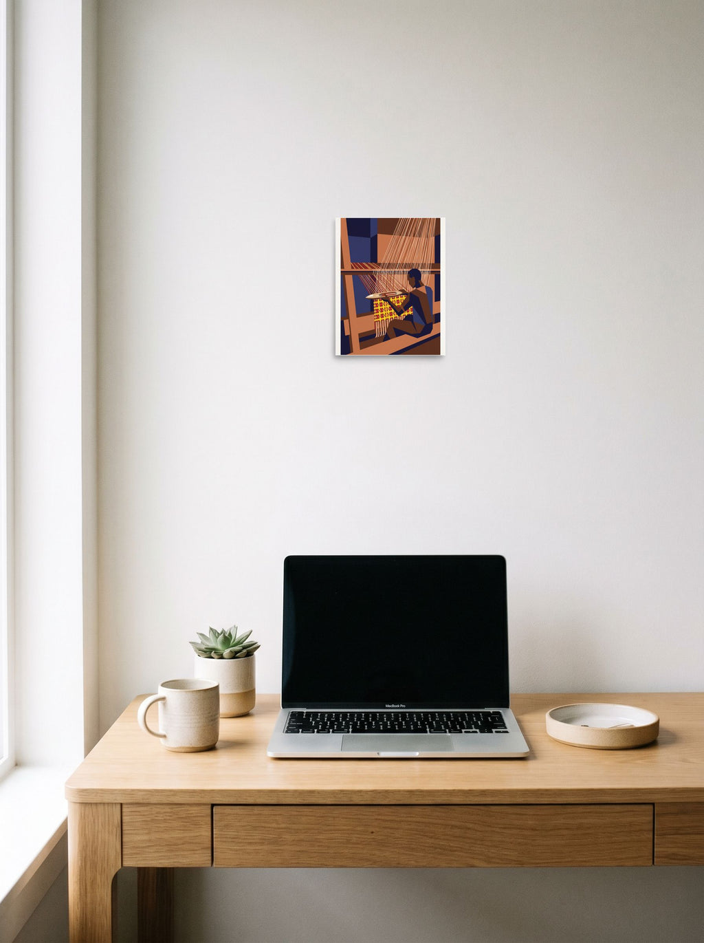 The unframed paper print 'The Kente Weaver' hanging above a worktable with a laptop, shown at 8x10 inch.