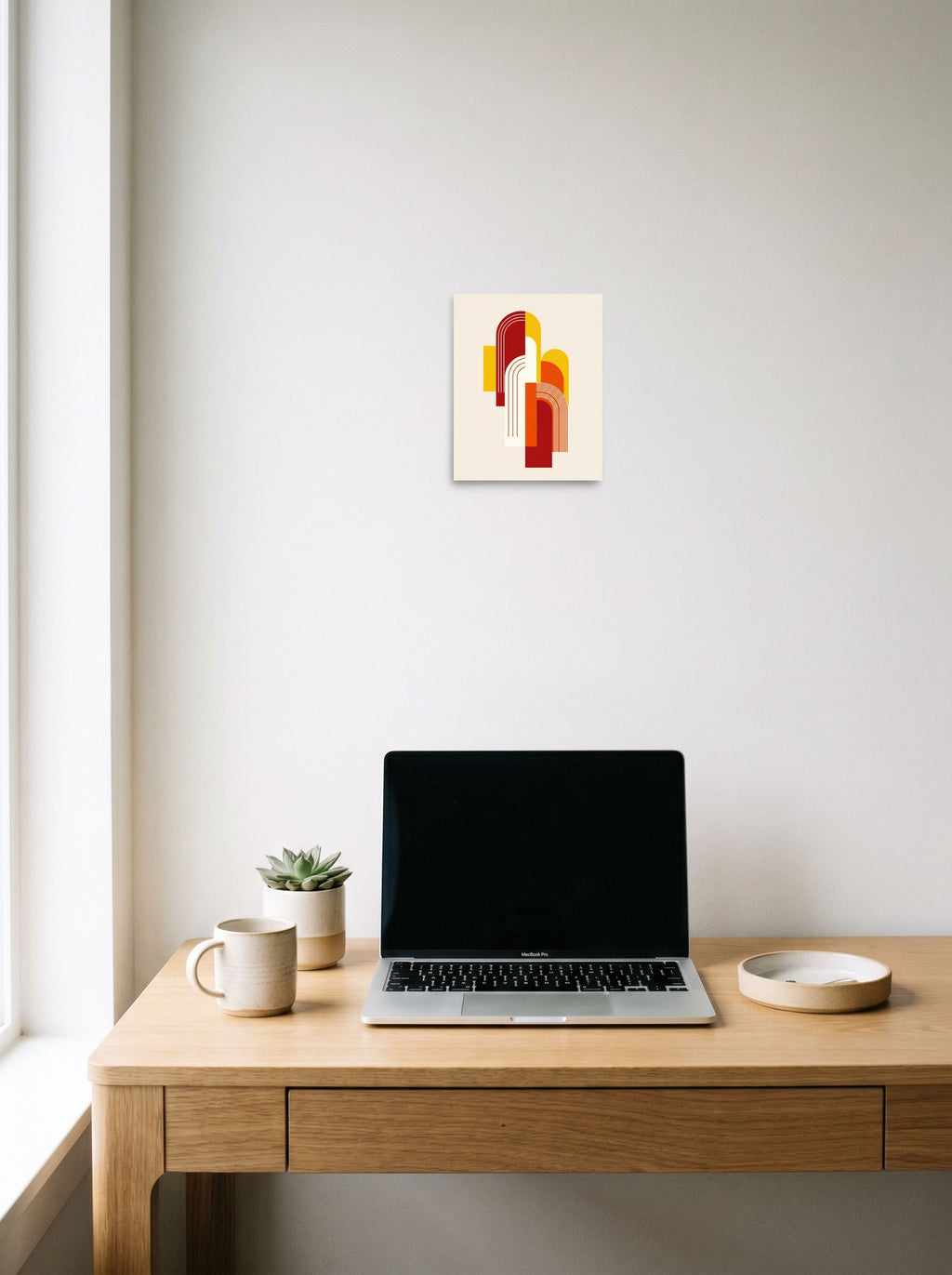 A 8x10 inch unframed paper Geometric abstract art print of 'Sunset Arches' hanging above a worktable with a laptop.